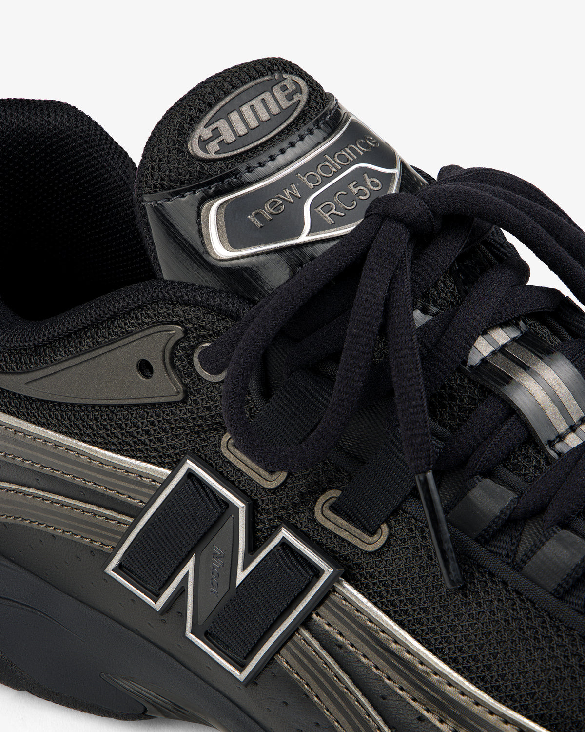 Close-up of a black ALD / New Balance RC56 sneaker with prominent logo, black laces, and mesh and leather details.