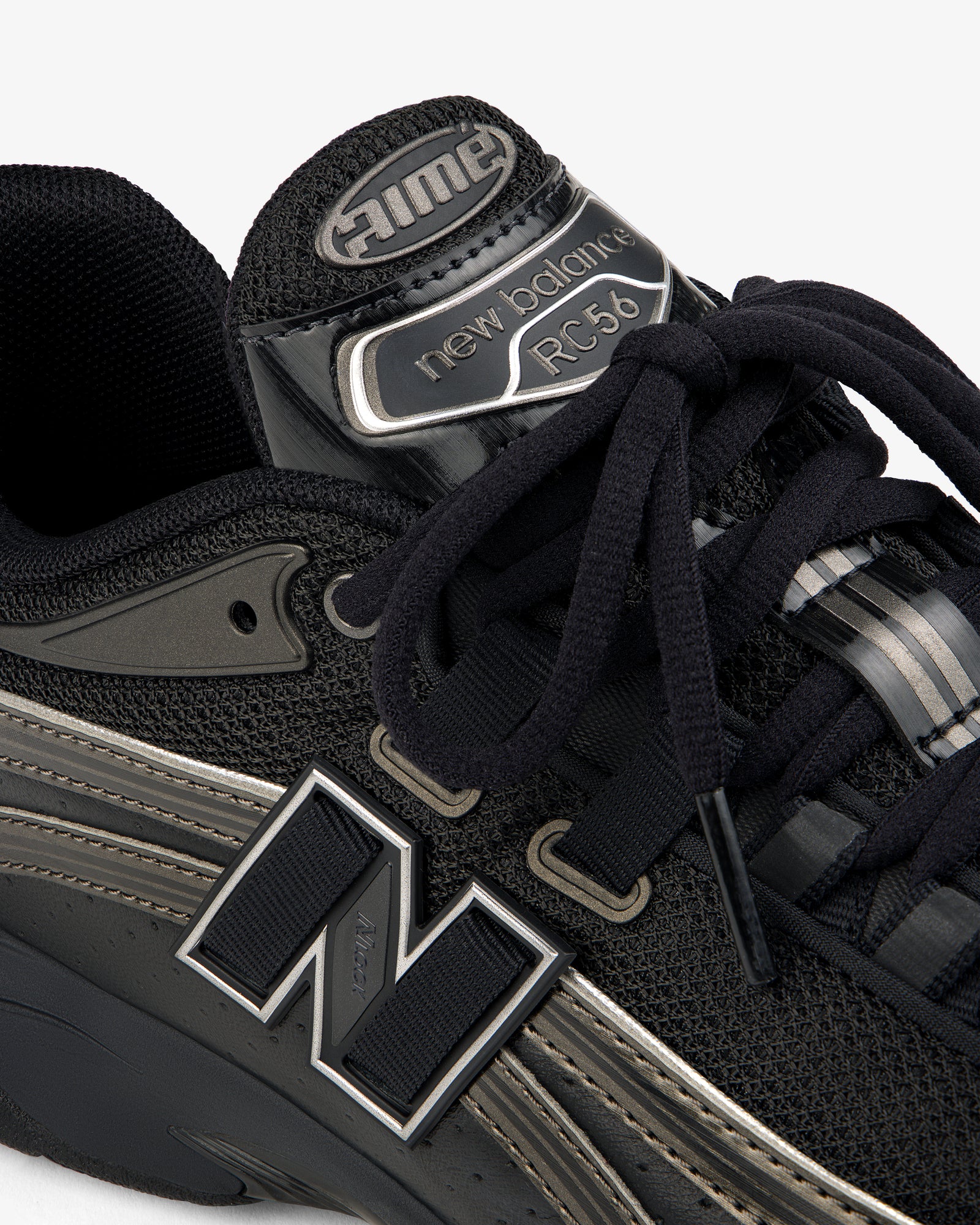 Close-up of a black ALD / New Balance RC56 sneaker with prominent logo, black laces, and mesh and leather details.