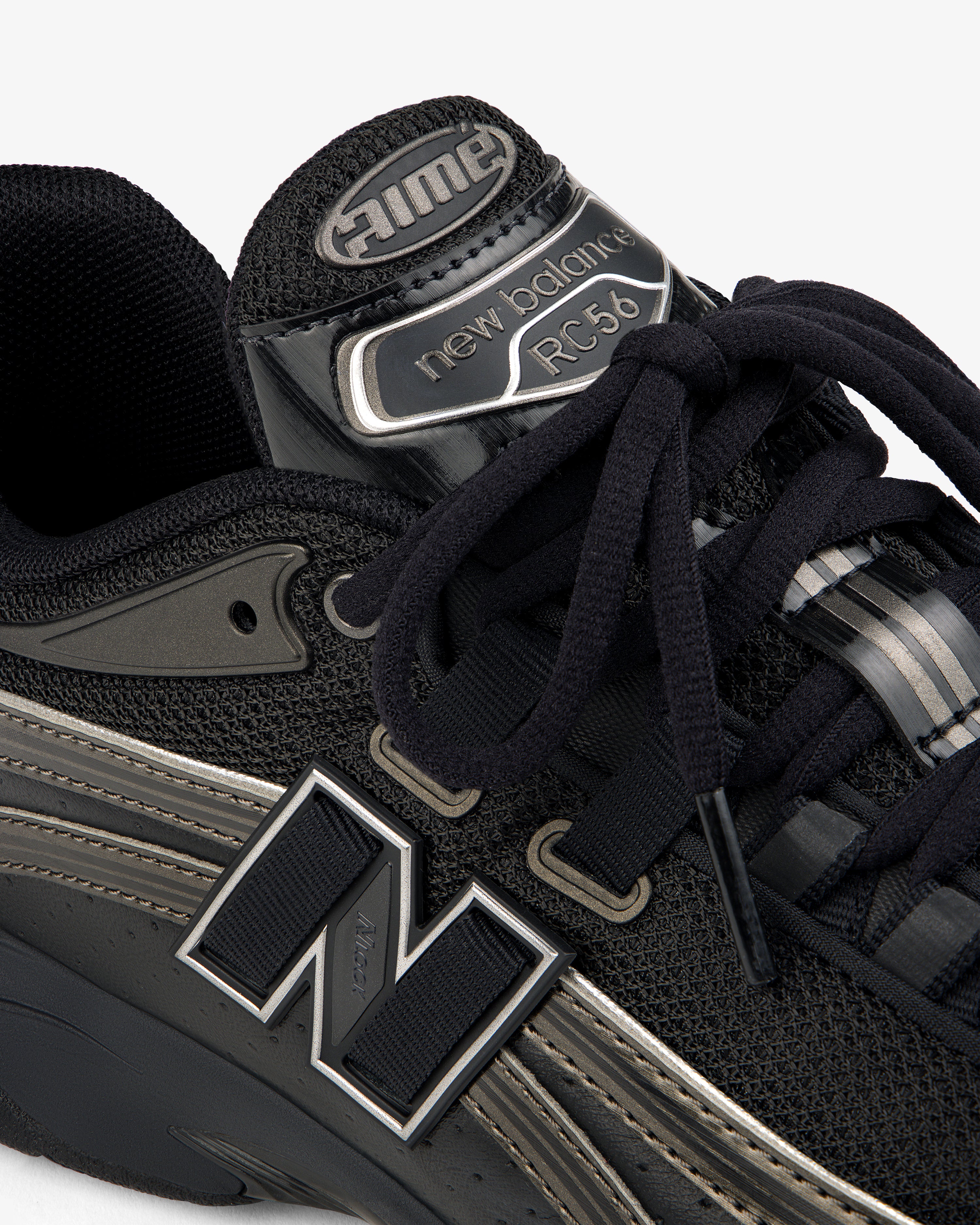 Close-up of a black ALD / New Balance RC56 sneaker with prominent logo, black laces, and mesh and leather details.