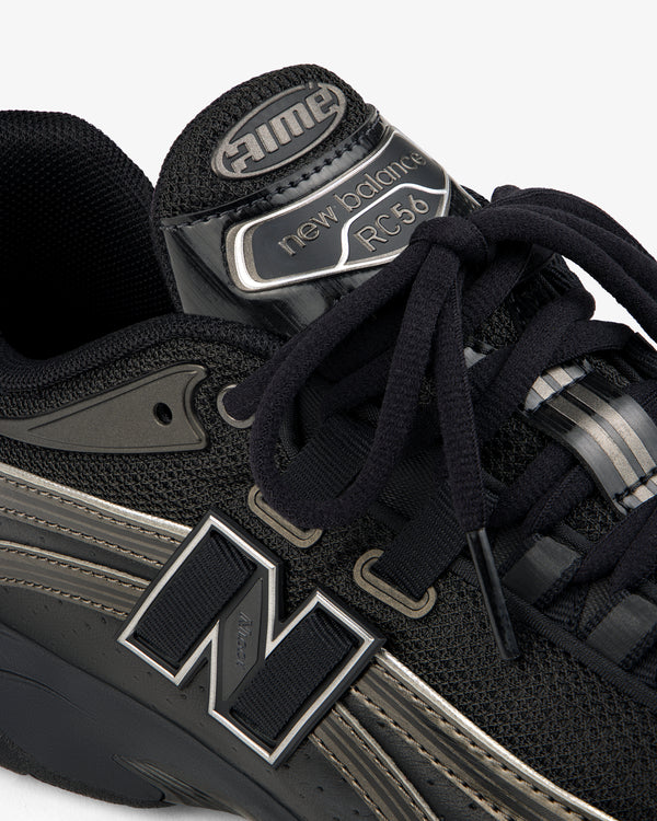 Close-up of a black ALD / New Balance RC56 sneaker with prominent logo, black laces, and mesh and leather details.