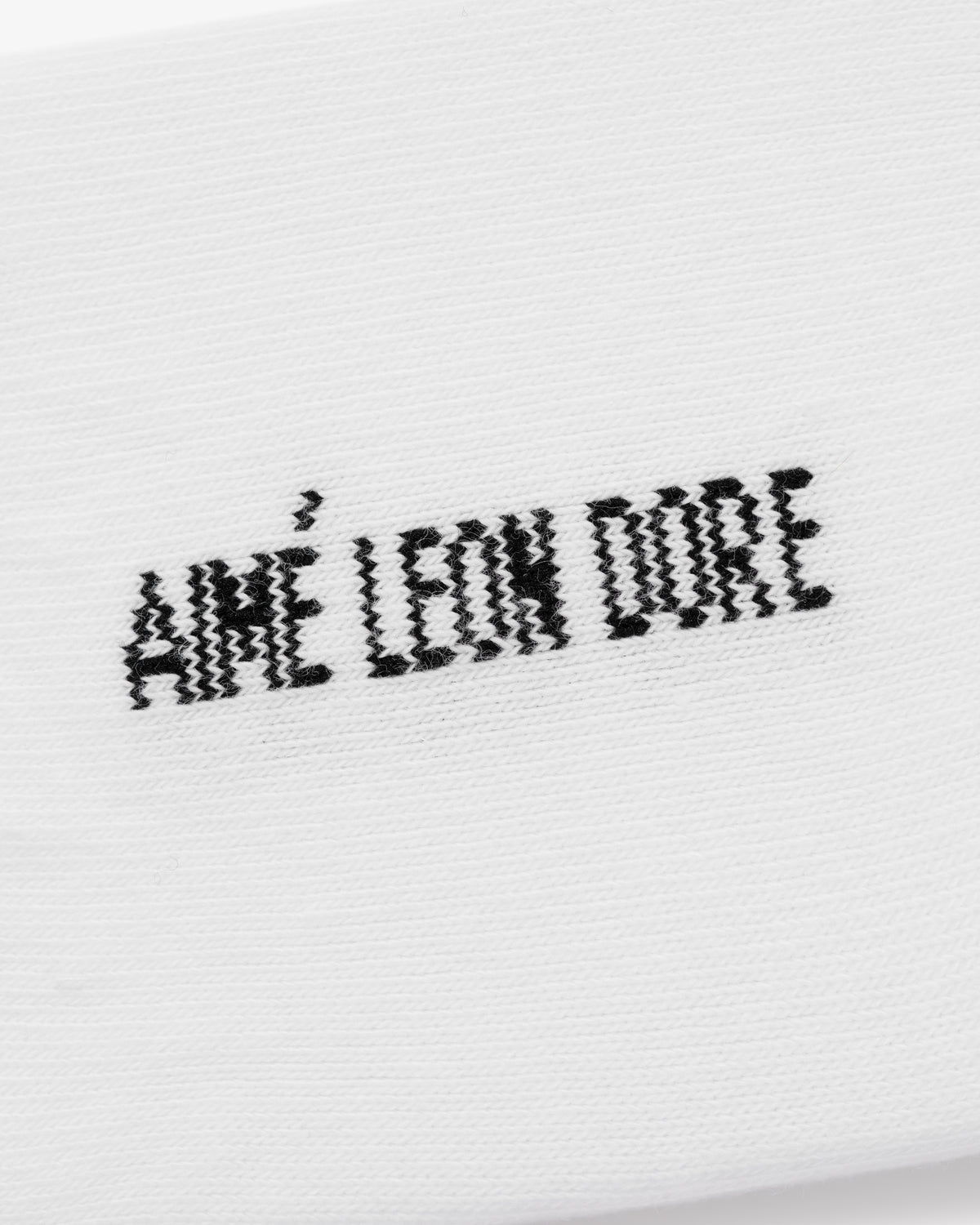 White ankle socks with black, pixelated AMÉ LEON DORE text embroidered; sold as a 3-pack.