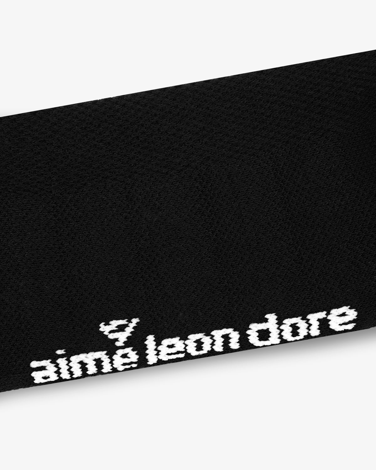 Close-up of black ALD Golf Performance Ankle Sock with aimé leon dore embroidered in white near the edge.