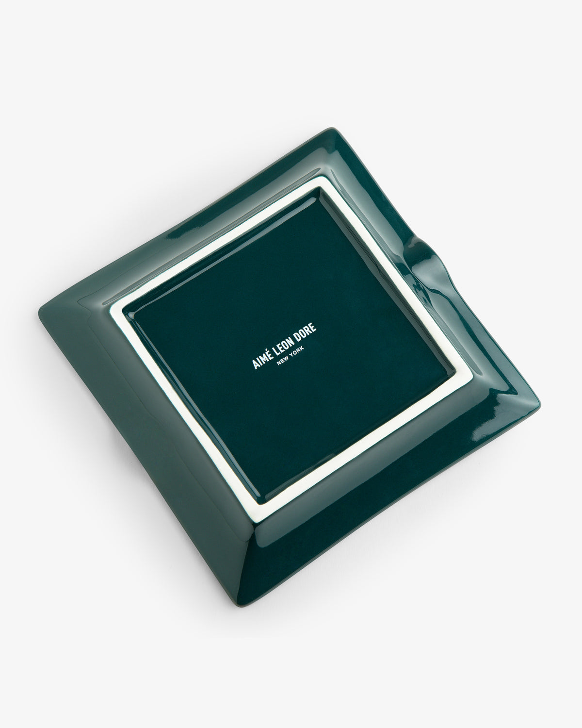 Unisphere Ashtray: dark green square with white border and Aimé Leon Dore text in the center, on a white background.