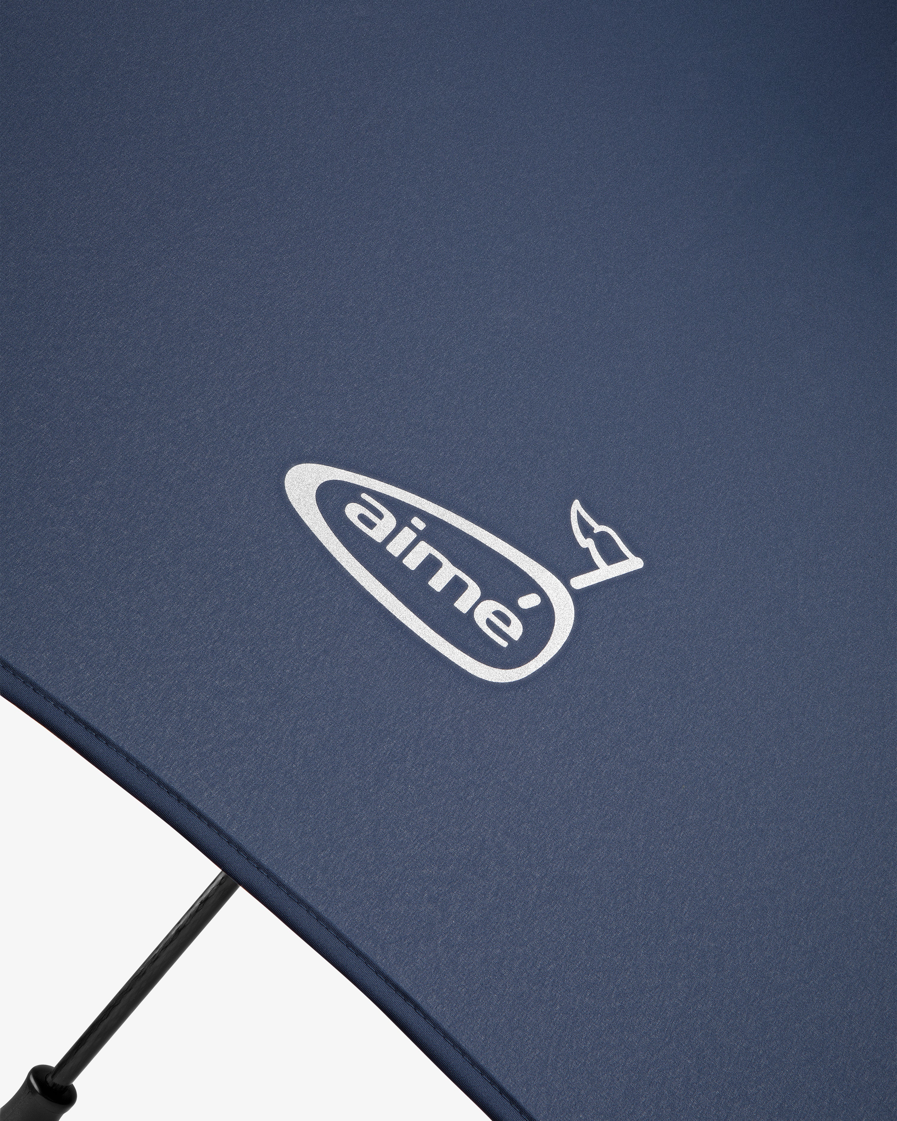 Close-up of the ALD Golf Spectator Umbrella in navy blue with "aimé" and a small bird logo printed in white.