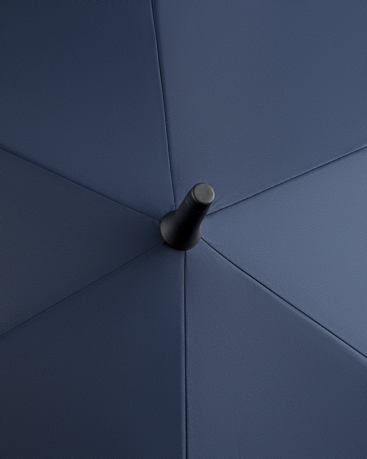 Close-up of the ALD Golf Spectator Umbrella's top center, highlighting its dark blue fabric panels and central tip.
