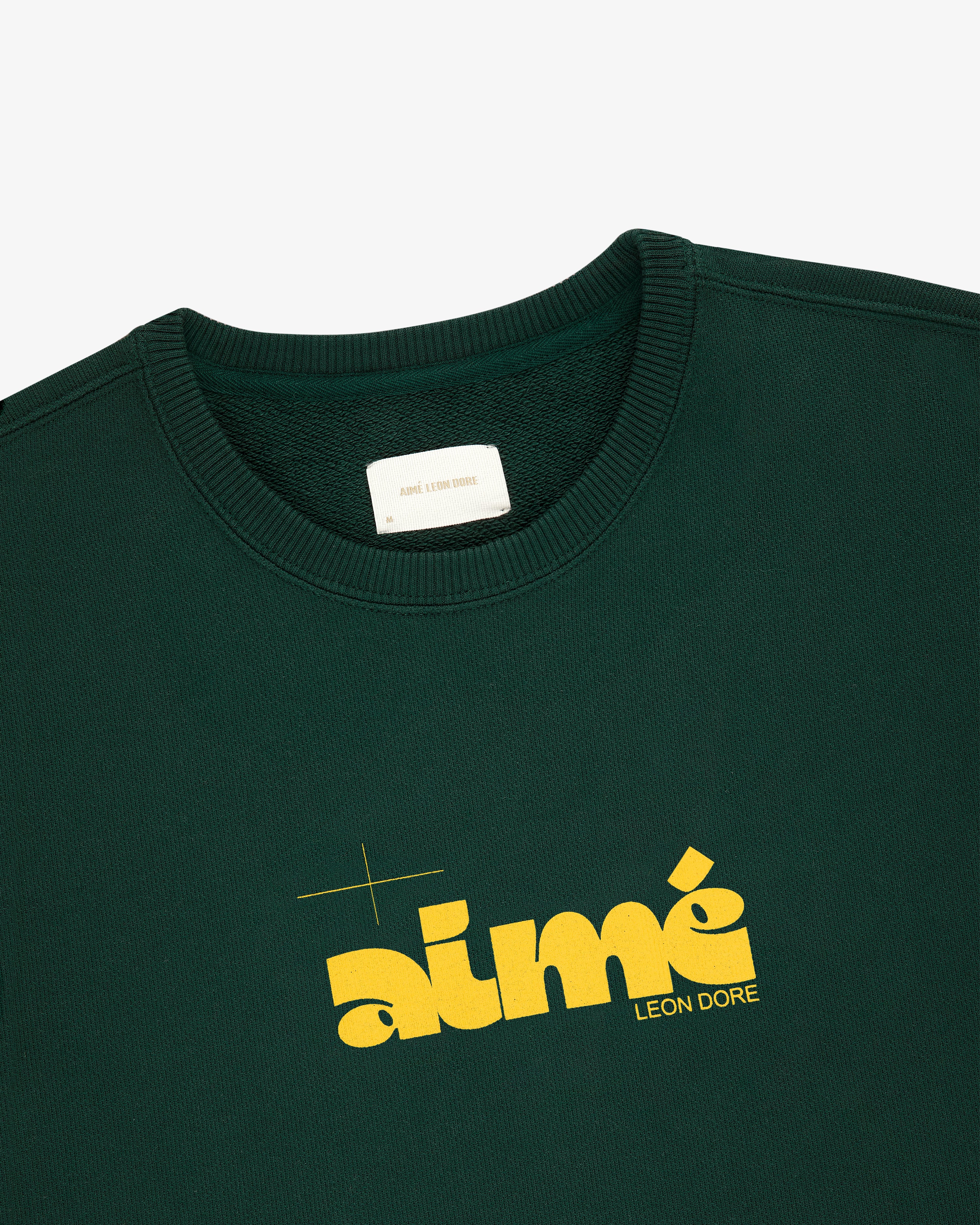 Drafting Logo Crewneck Sweatshirt in dark green with bold yellow aimé LEON DORE print on the front.