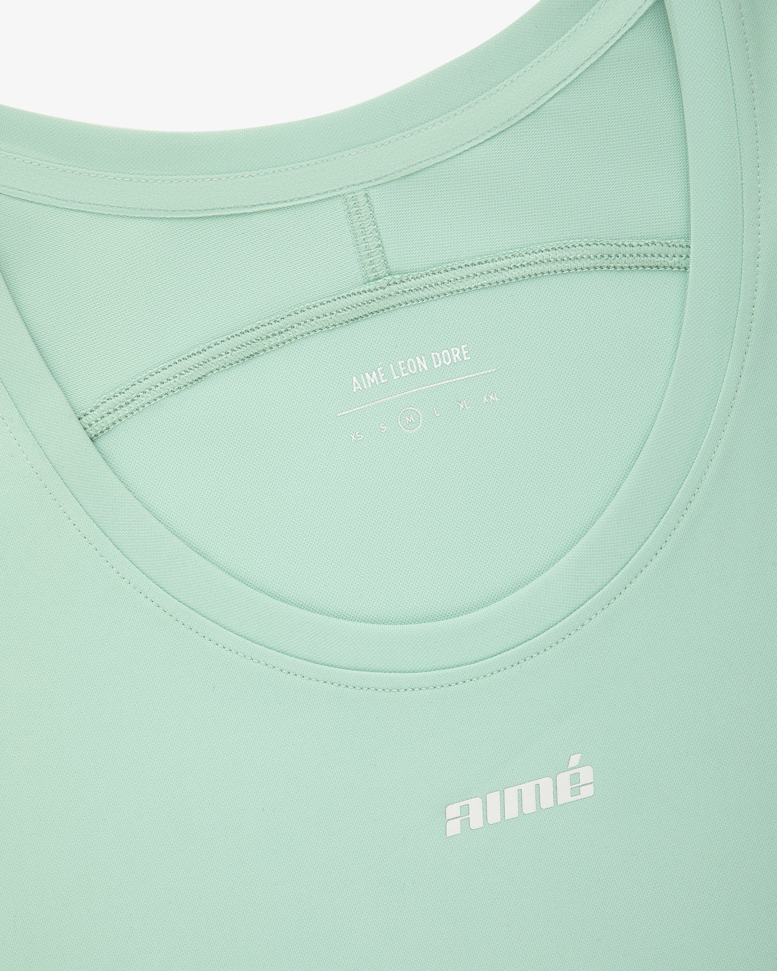 Close-up of the Aimé Performance Tank Top in light green with AIMÉ LEON DORE branding printed in white.