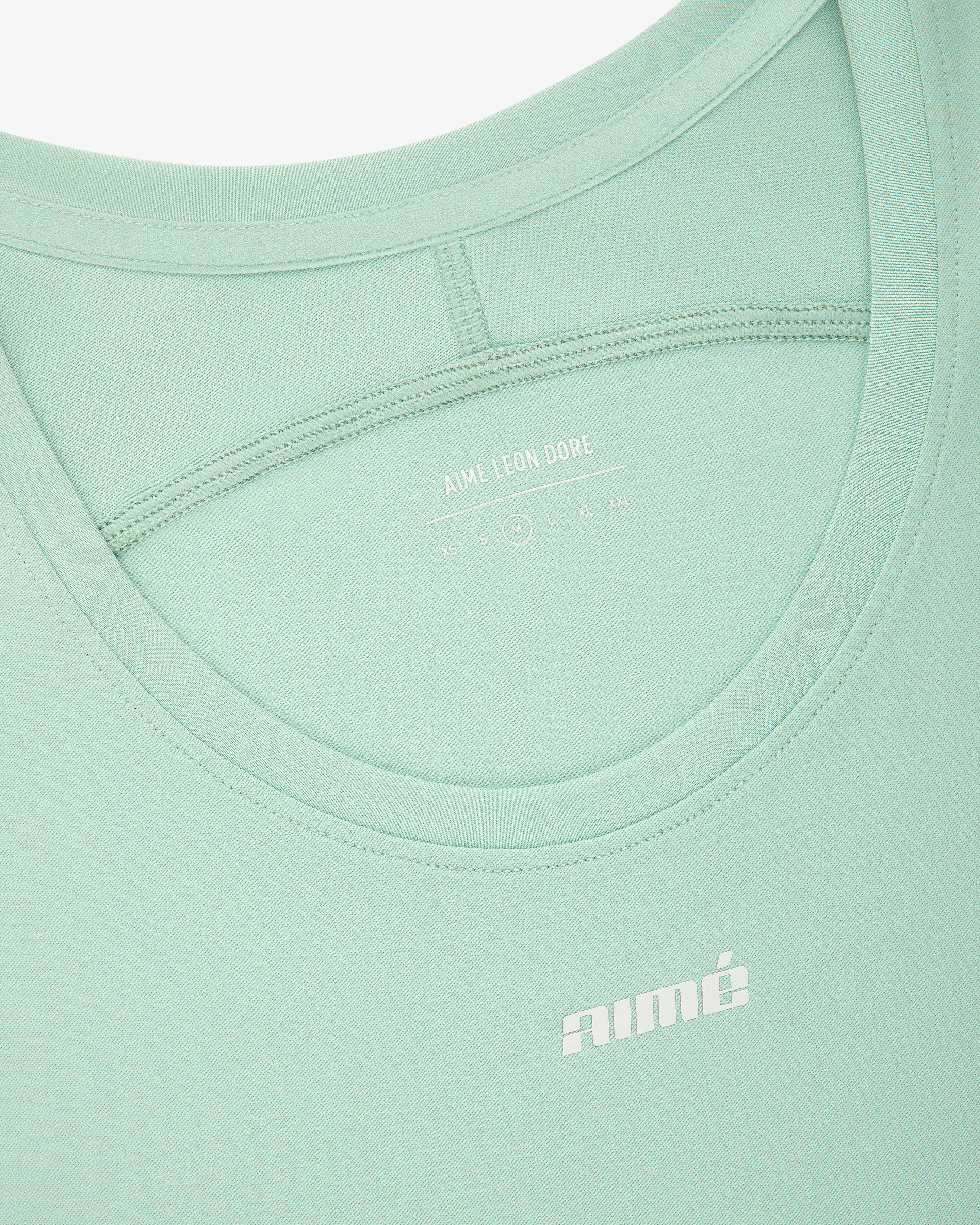 Close-up of the Aimé Performance Tank Top in light green with AIMÉ LEON DORE branding printed in white.