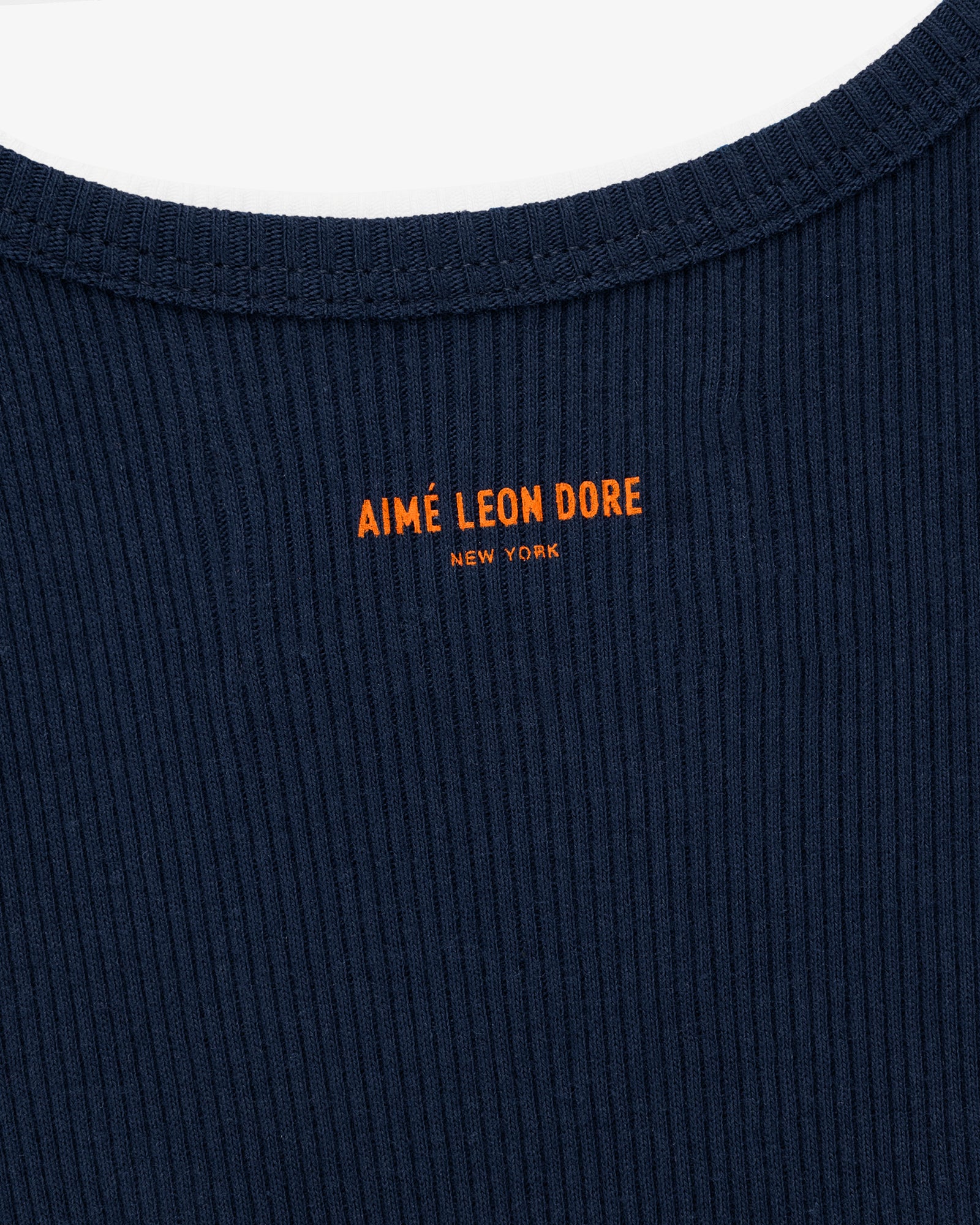 Close-up of the Mets Tank Top in navy ribbed fabric with orange AIMÉ LEON DORE NEW YORK text near the collar.