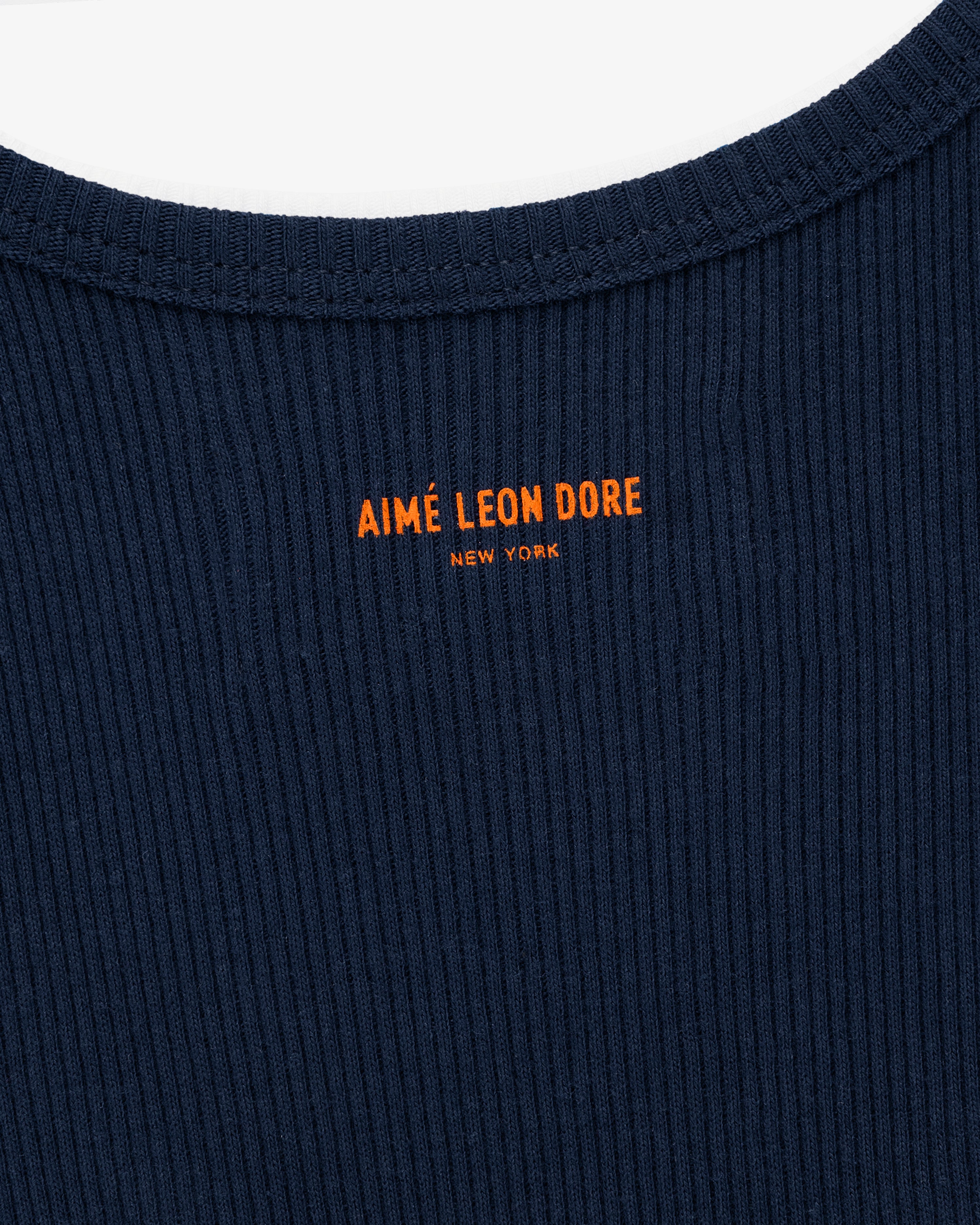 Close-up of the Mets Tank Top in navy ribbed fabric with orange AIMÉ LEON DORE NEW YORK text near the collar.