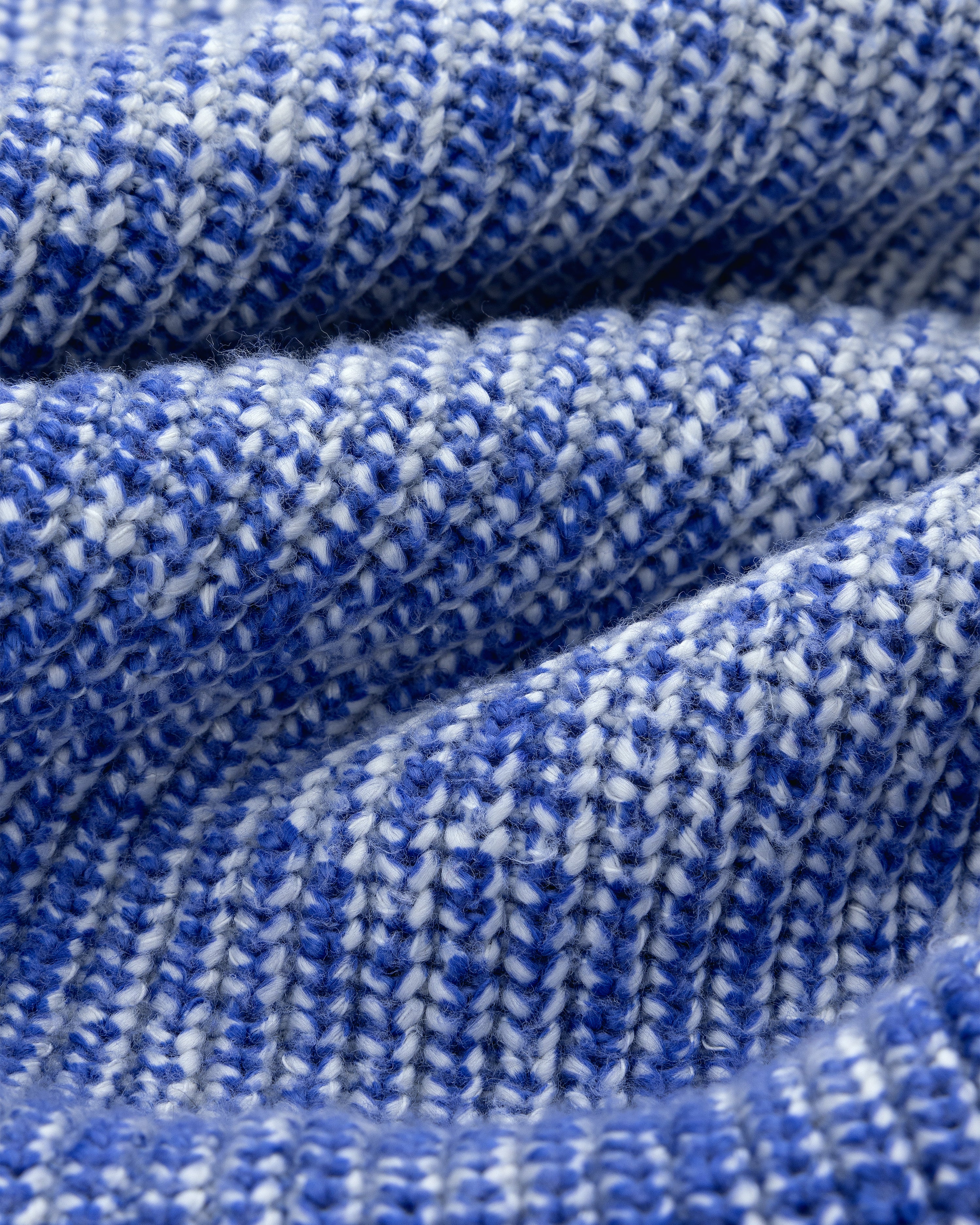 Close-up of Kalloni Shaker Stitch Sweater in blue and white with textured, wavy knit folds.