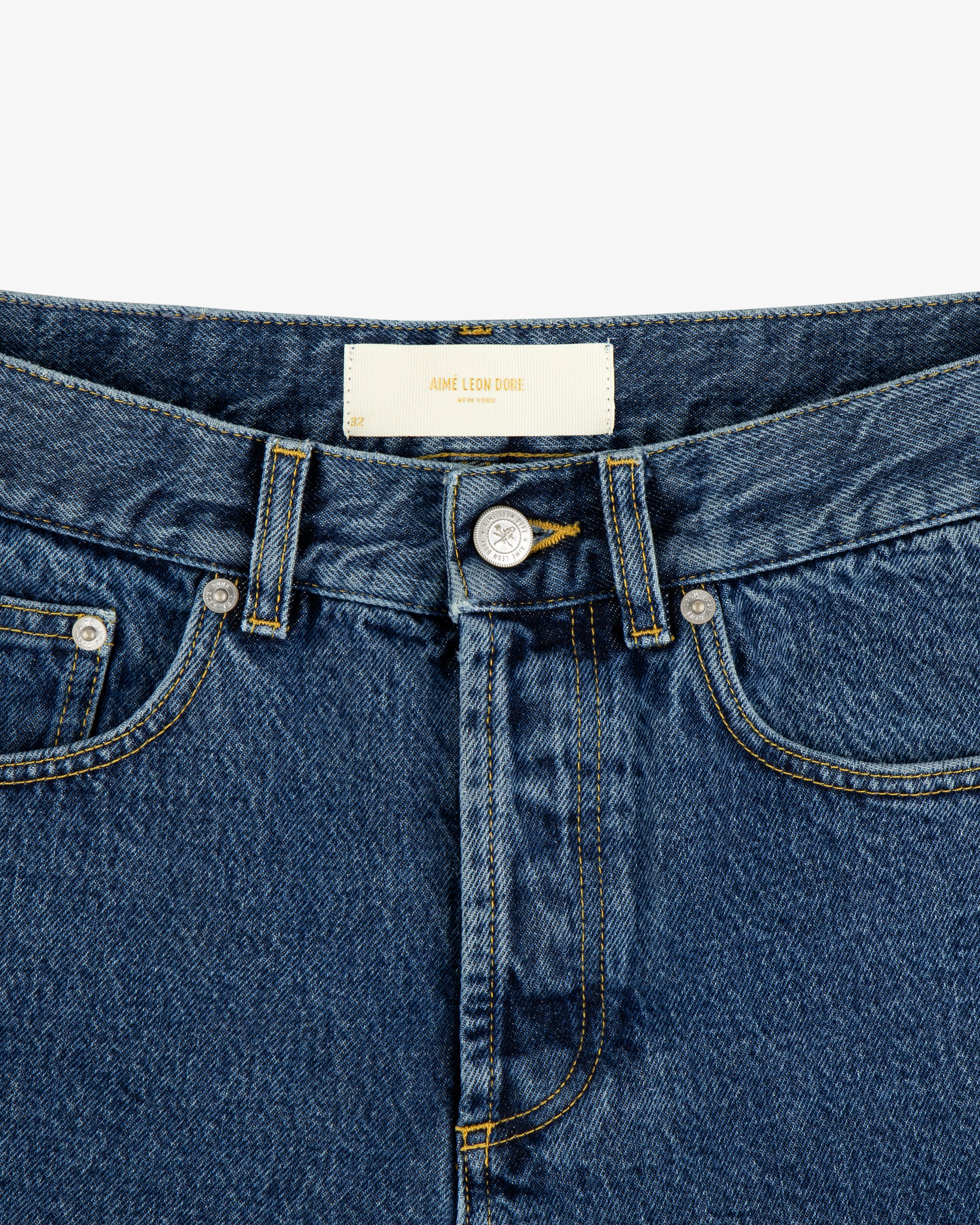 Close-up of ALD Straight Fit Denim in blue with a button fly, front pockets, and a white waistband label.