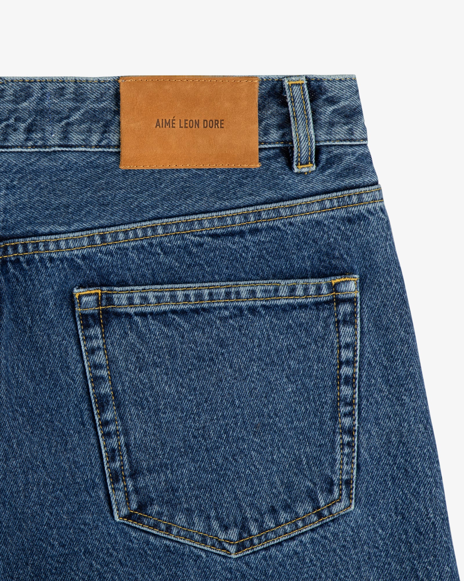 Back pocket of ALD Straight Fit Denim with a brown leather patch labeled AIMÉ LEON DORE above the pocket.