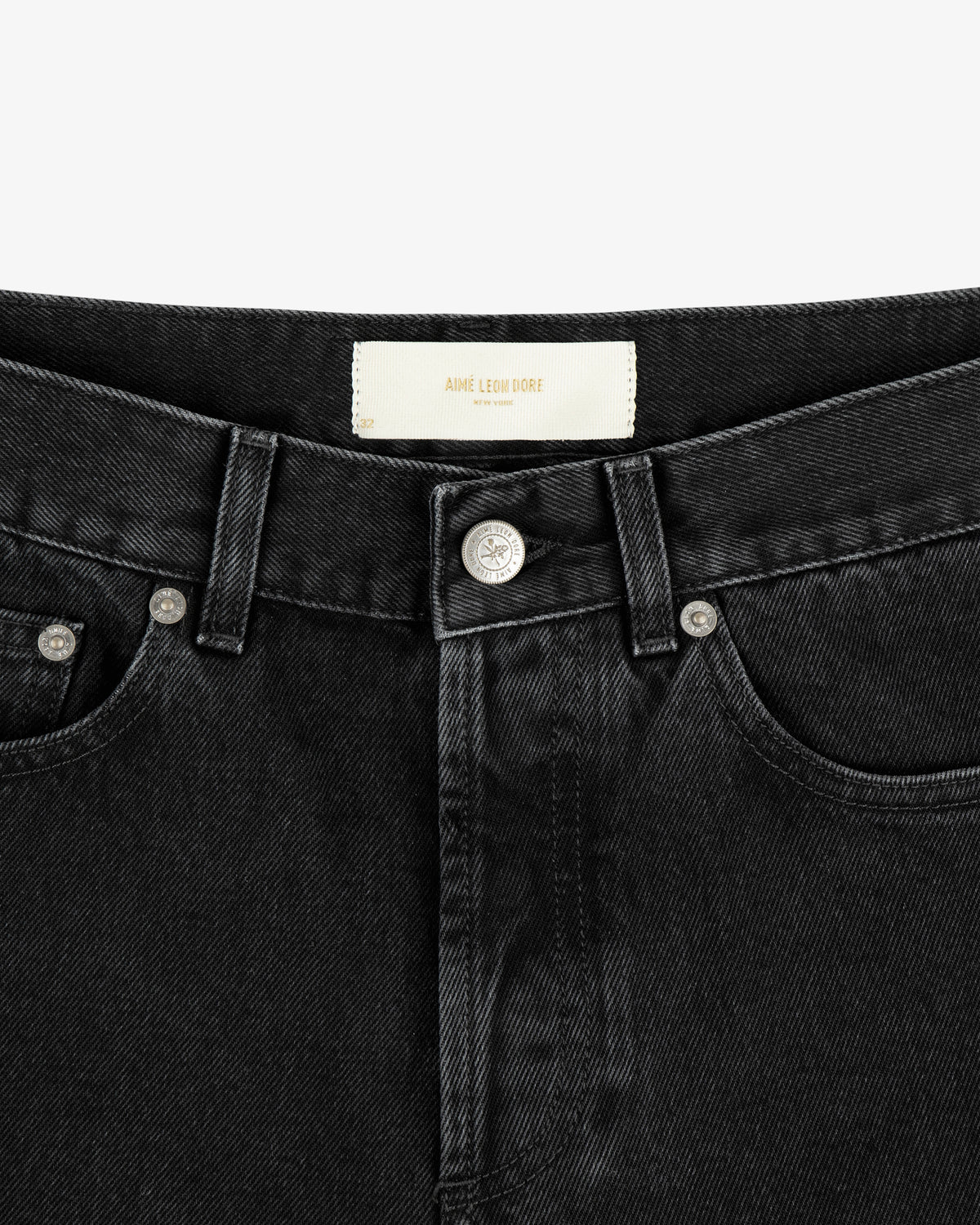 Close-up of the waistband and front button of ALD Straight Fit Denim in black, showing a white label inside.