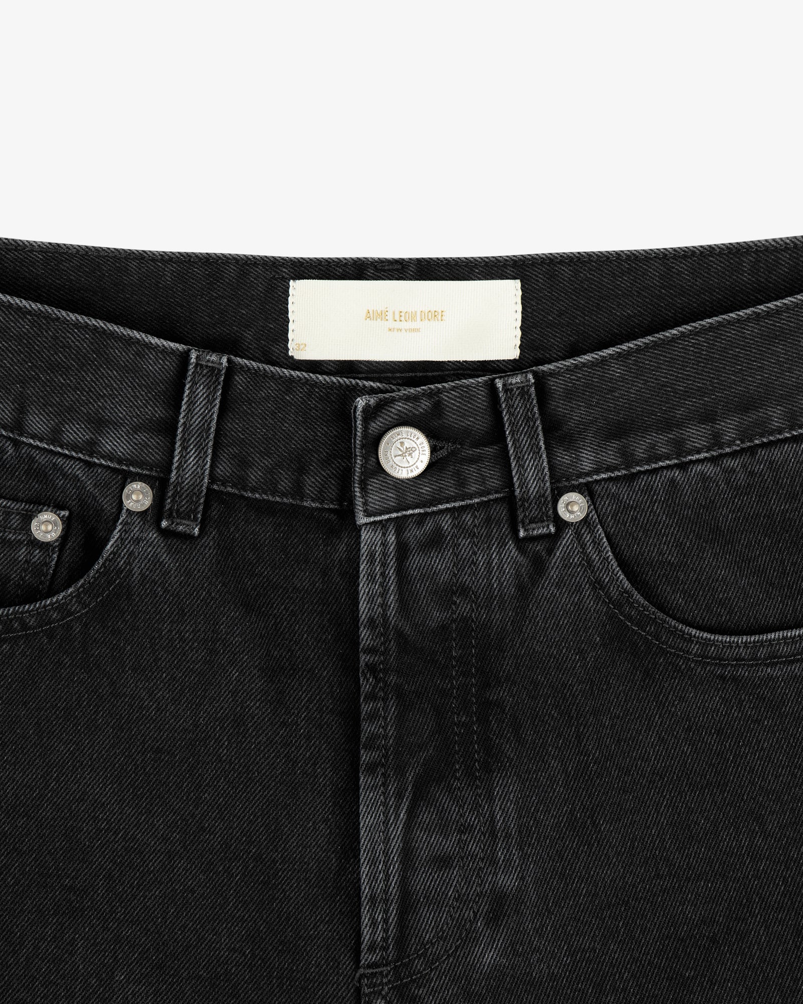 Close-up of the waistband and front button of ALD Straight Fit Denim in black, showing a white label inside.