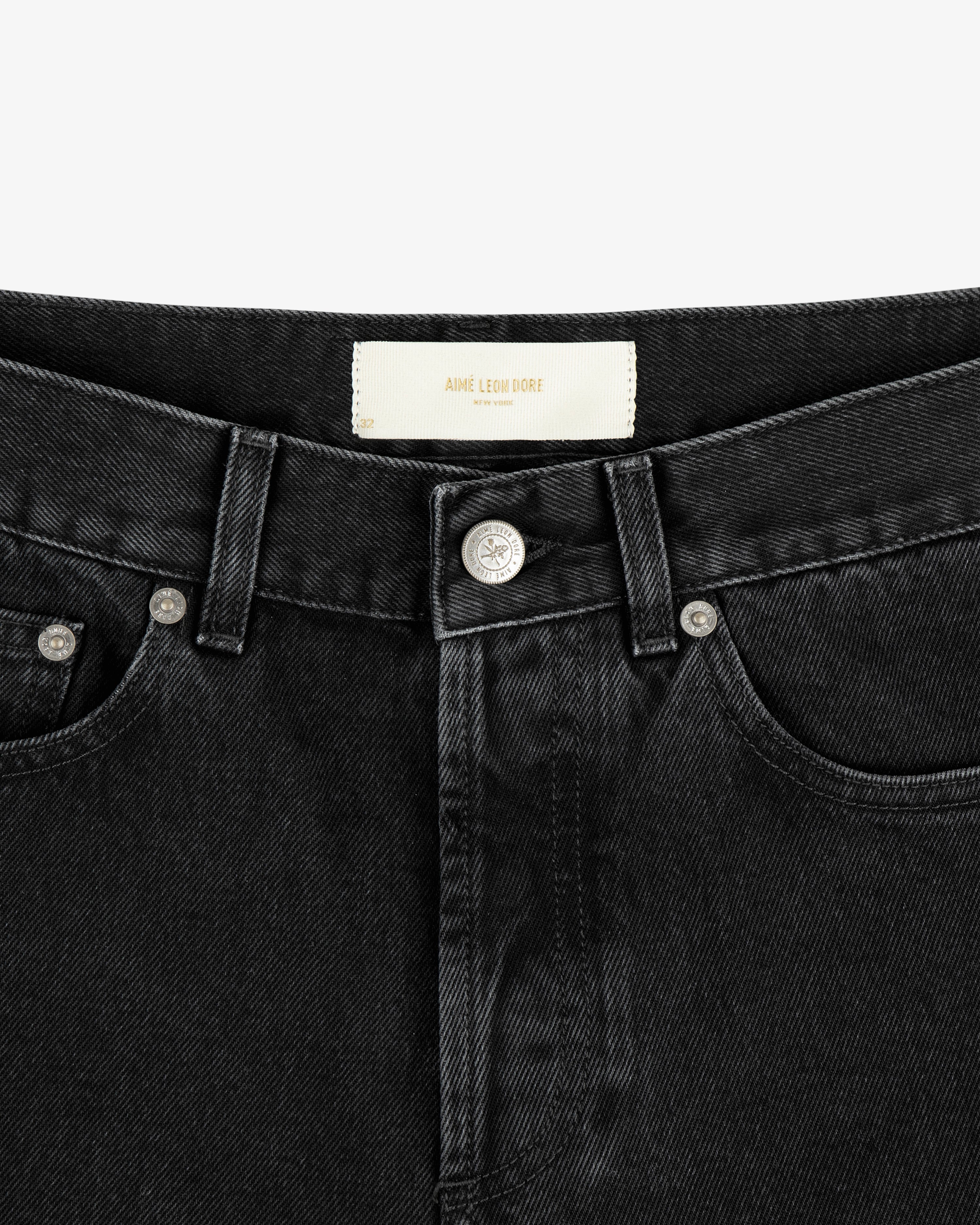 Close-up of the waistband and front button of ALD Straight Fit Denim in black, showing a white label inside.