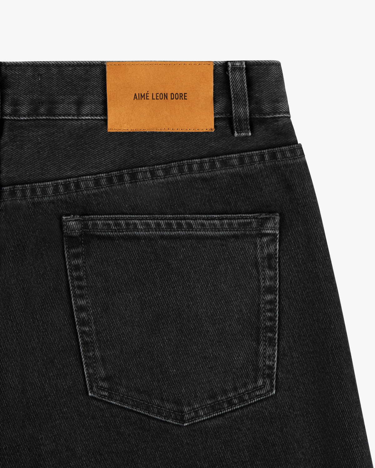 Close-up of ALD Straight Fit Denim in black with a tan leather AIMÉ LEON DORE patch above the back pocket.