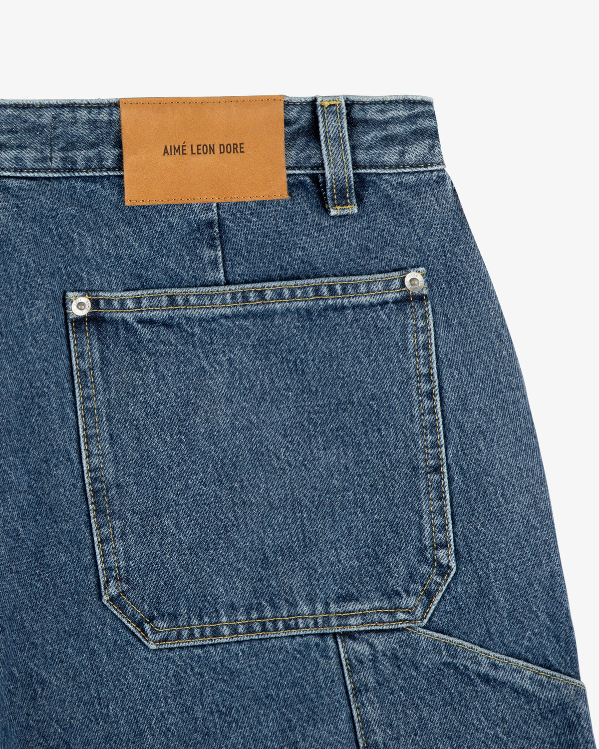 Close-up of blue Denim Carpenter Pant with a brown leather AIME LEON DORE patch above the back pocket.