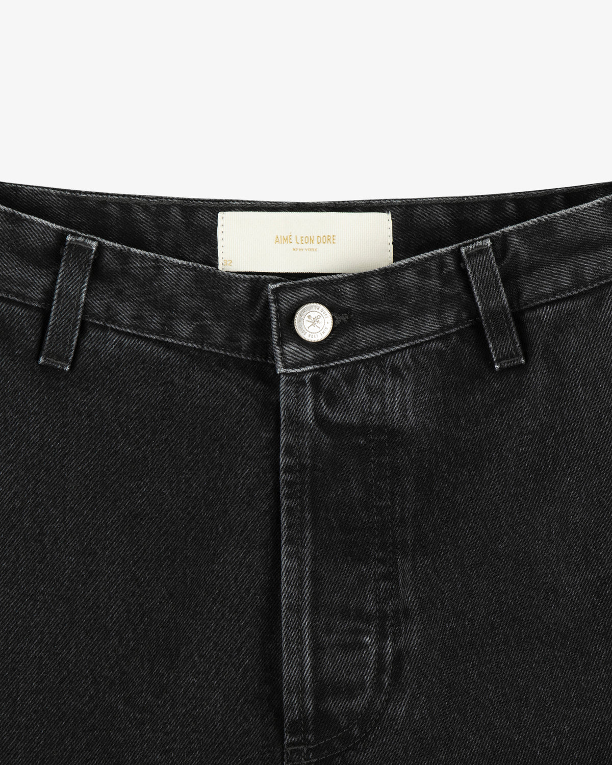 Close-up of the waistband and button of black Denim Carpenter Pant featuring an Aimé Leon Dore label inside.
