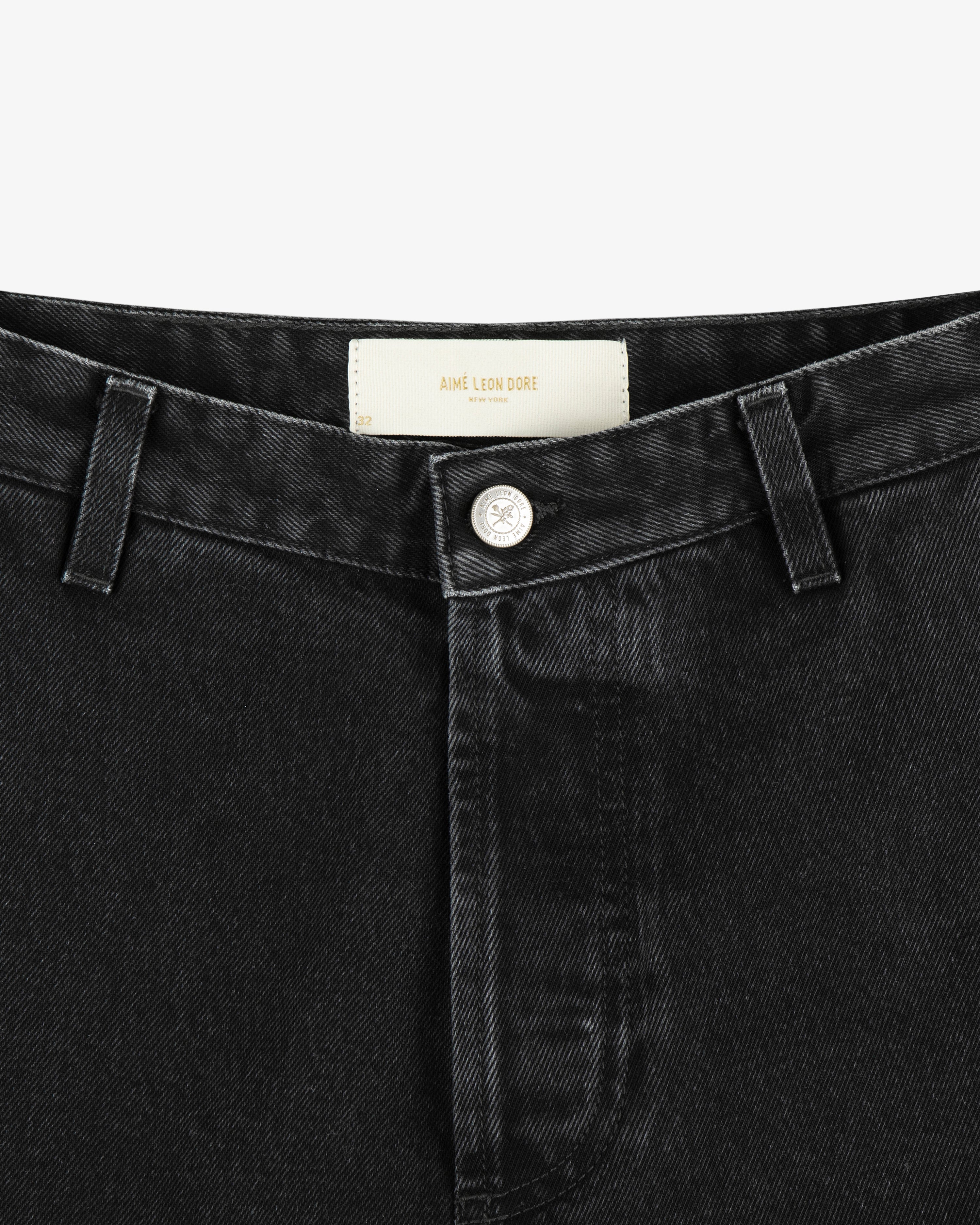 Close-up of the waistband and button of black Denim Carpenter Pant featuring an Aimé Leon Dore label inside.