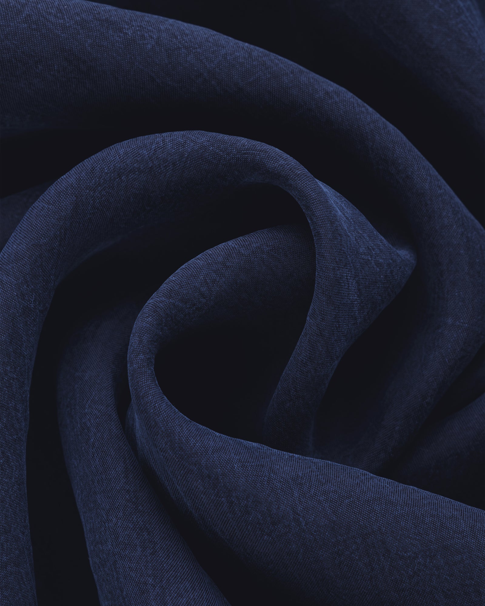 The Collarband Safari Shirt features dark blue fabric with soft folds and gentle curves for a textured look.