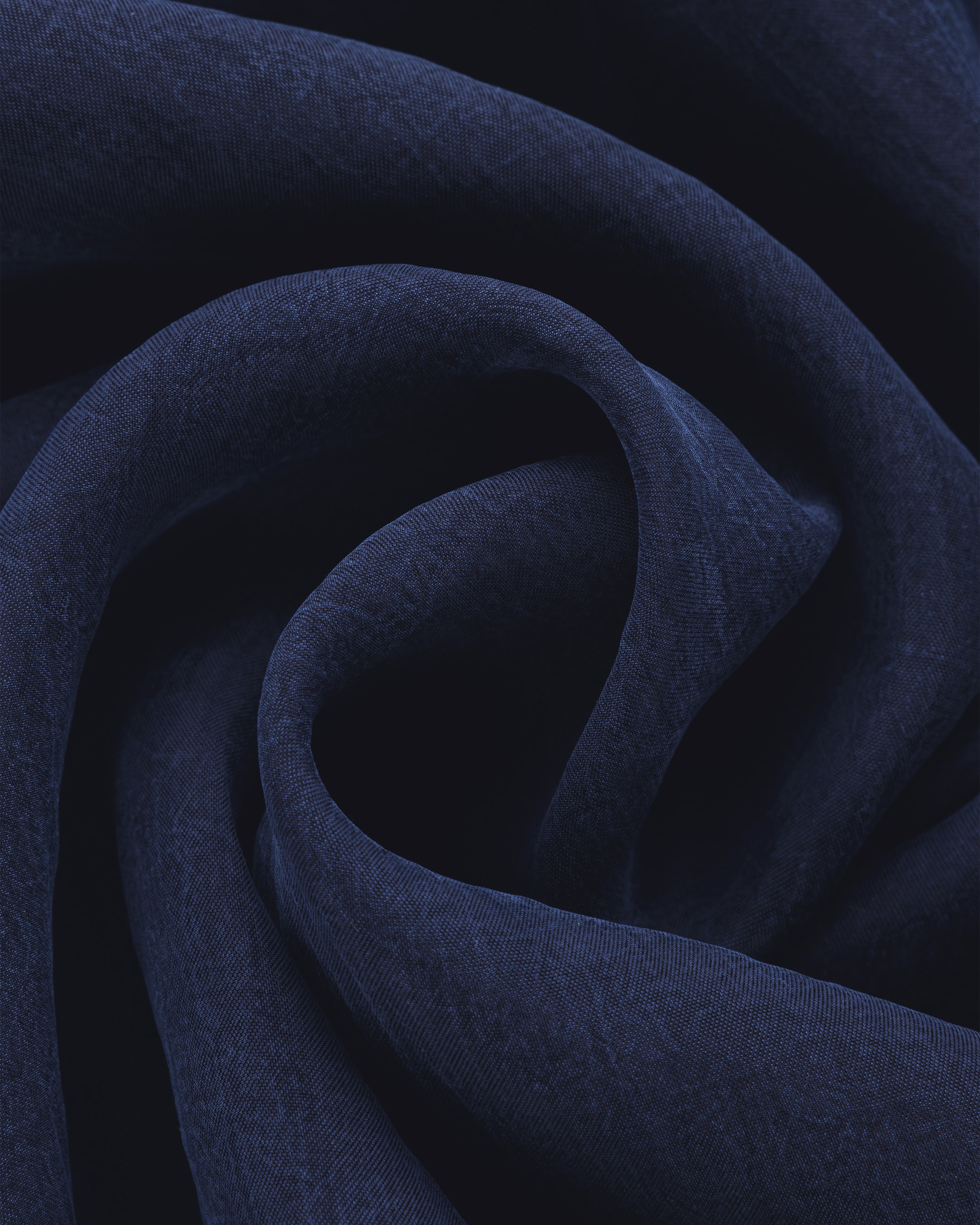 The Collarband Safari Shirt features dark blue fabric with soft folds and gentle curves for a textured look.