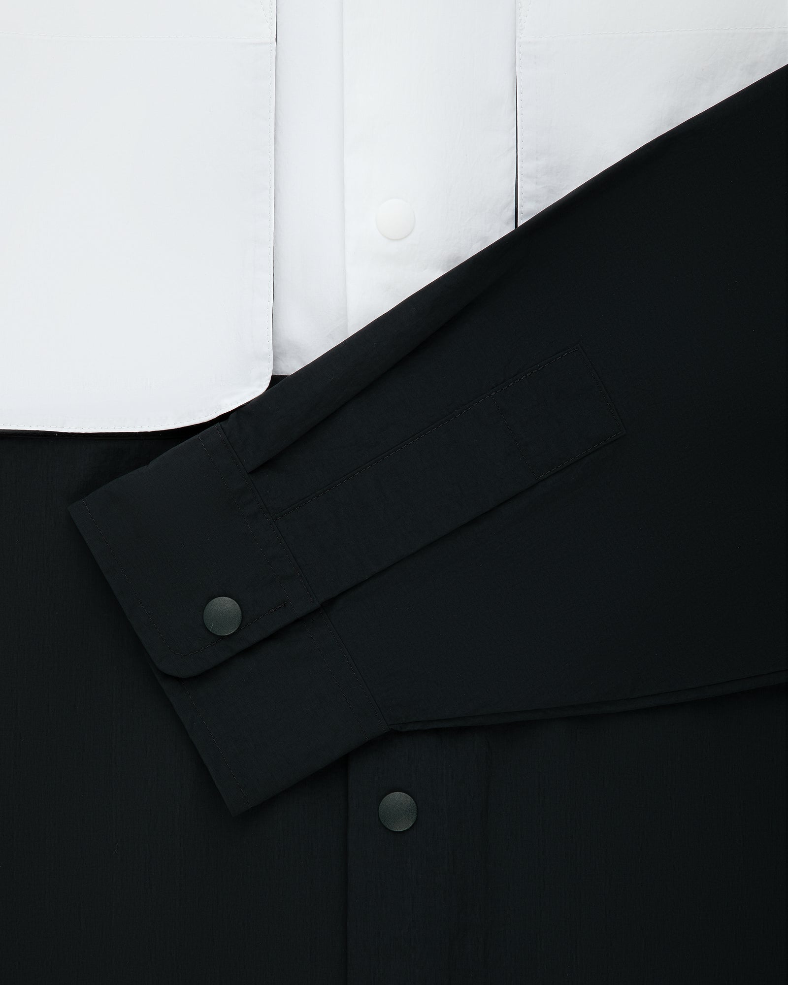 Colorblock Sport Shirt features a black sleeve with snaps over white, both in smooth fabric with matching buttons.