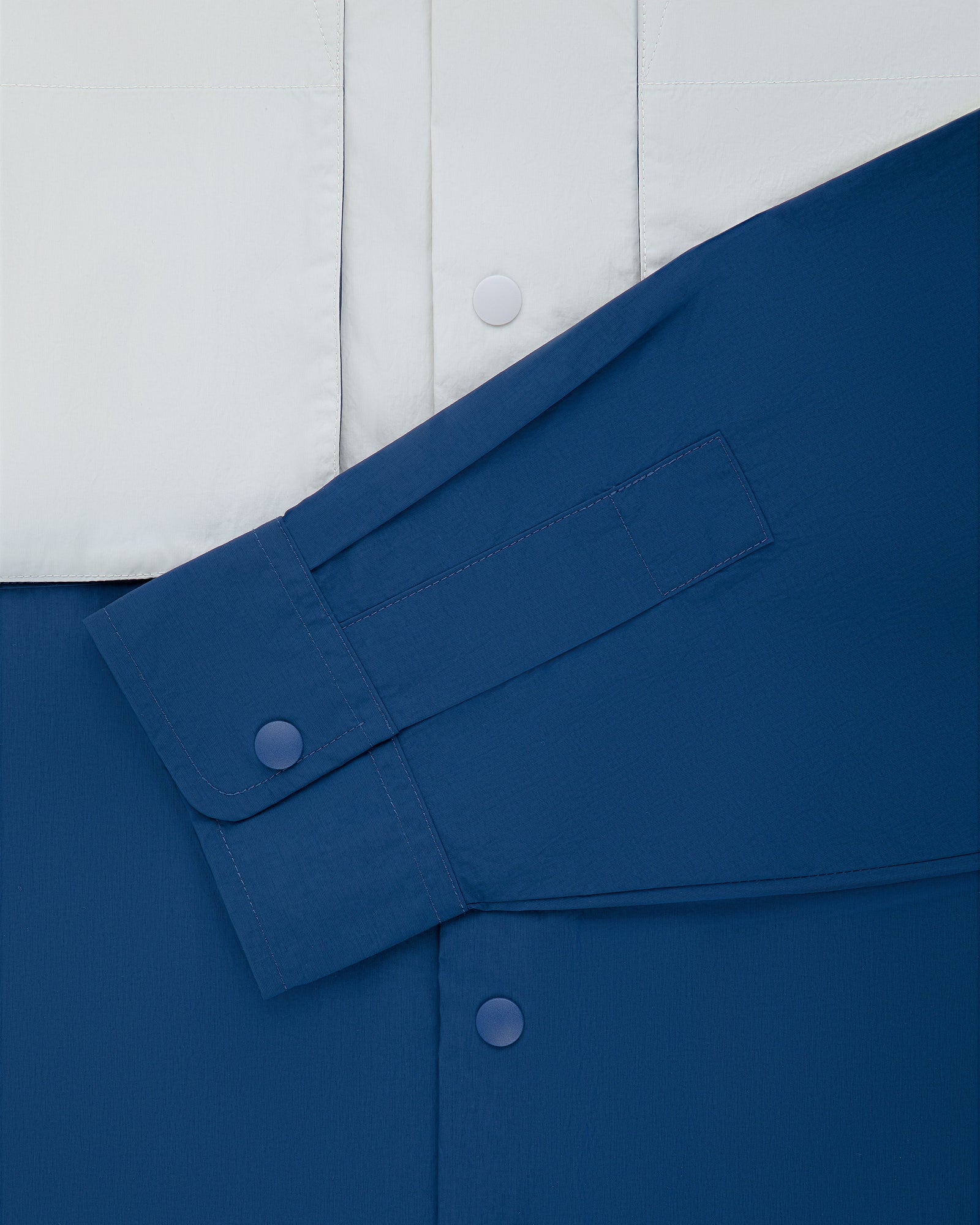 Colorblock Sport Shirt in blue and white with snap buttons and a single long sleeve laid diagonally on the front.
