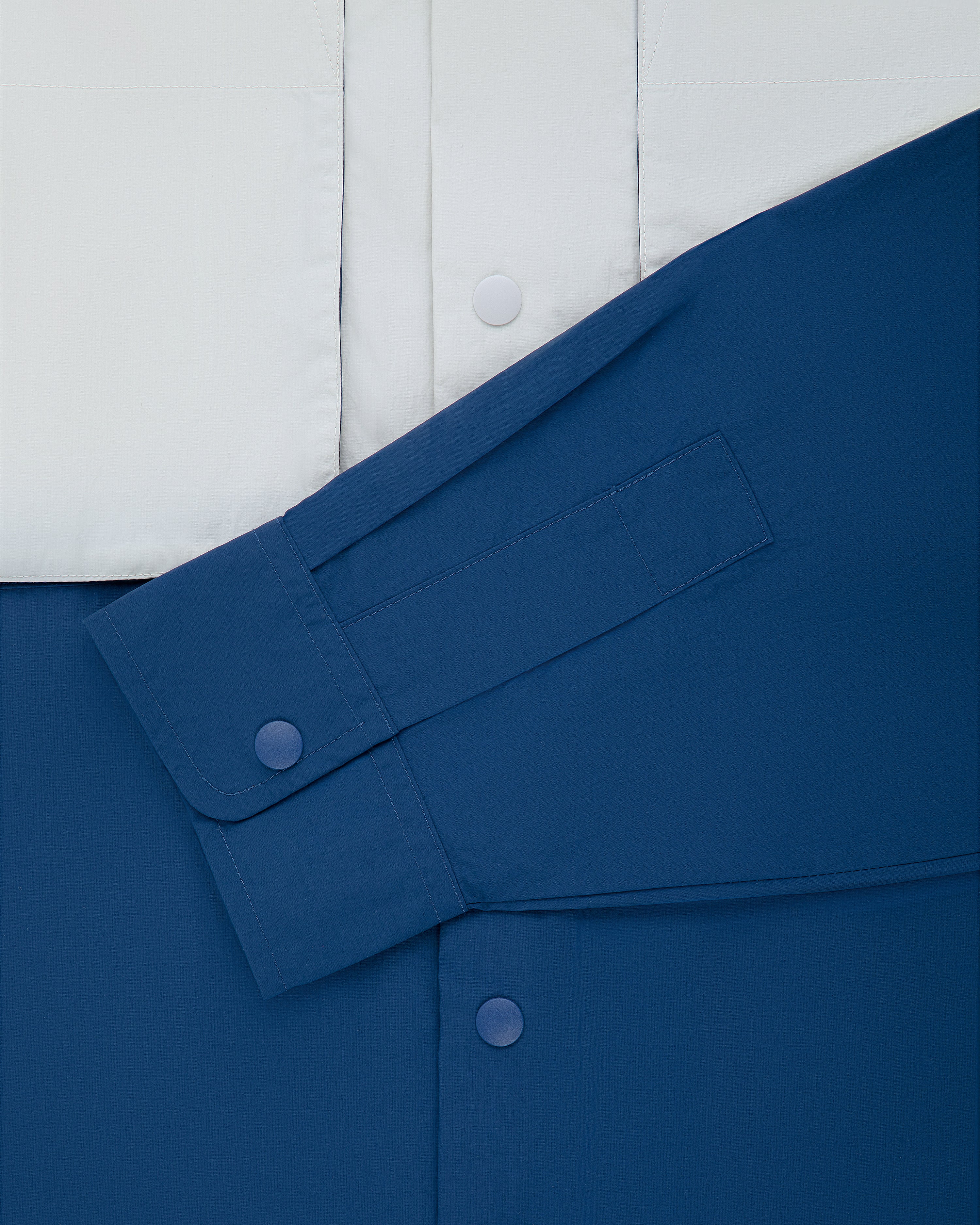 Colorblock Sport Shirt in blue and white with snap buttons and a single long sleeve laid diagonally on the front.