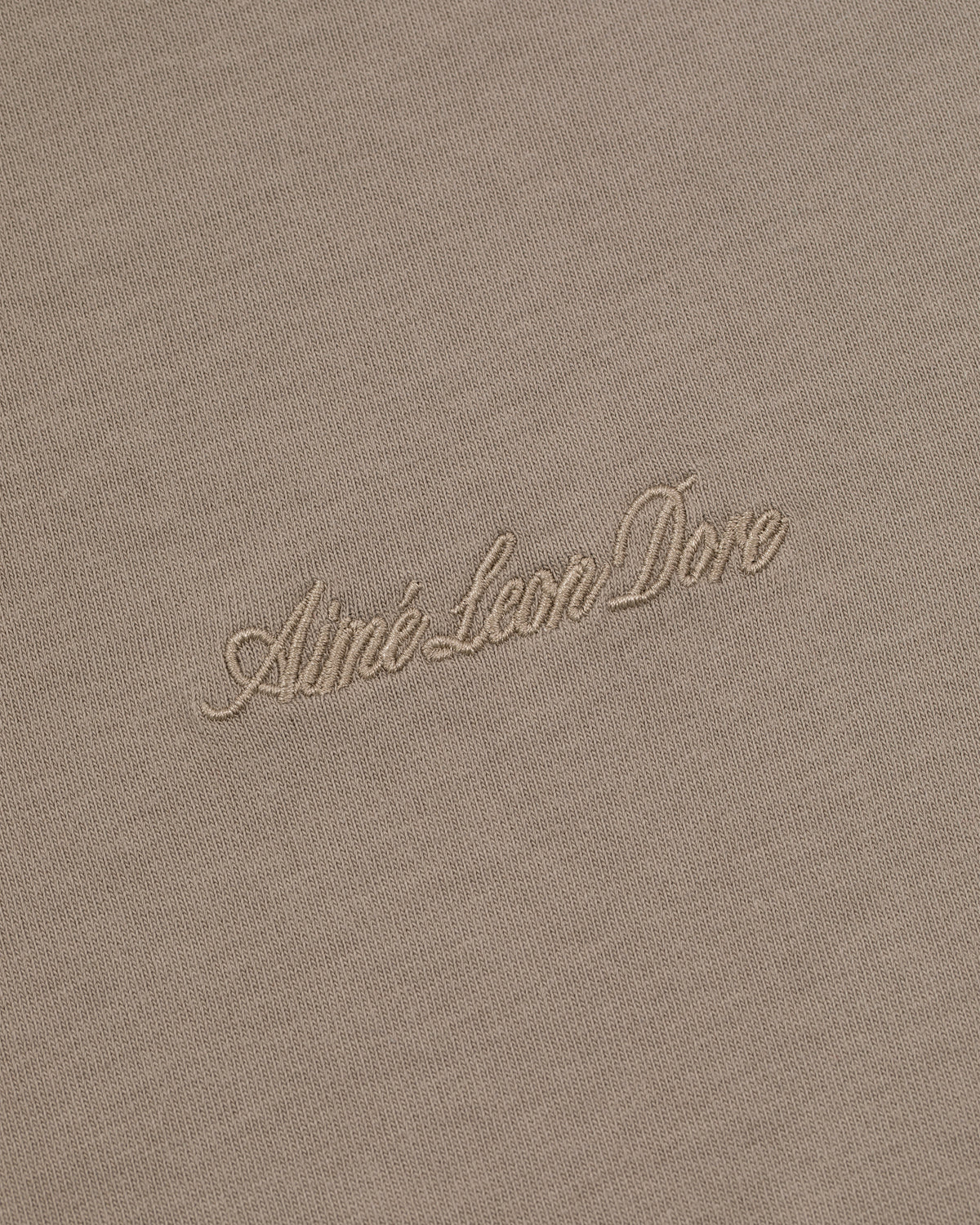 Beige Embroidered Logo Tee with Aimé Leon Dore in light cursive embroidery at the center.
