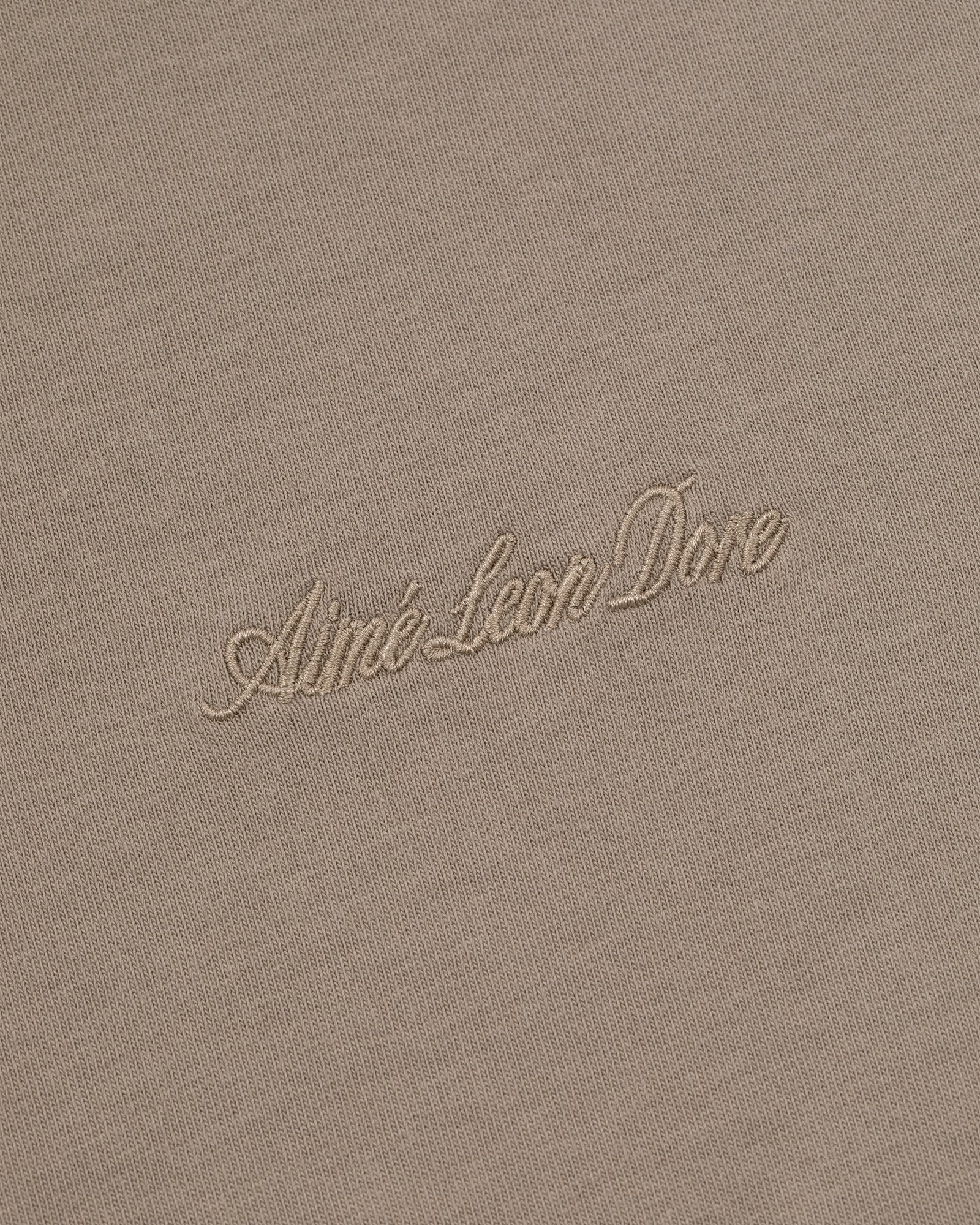 Beige Embroidered Logo Tee with Aimé Leon Dore in light cursive embroidery at the center.