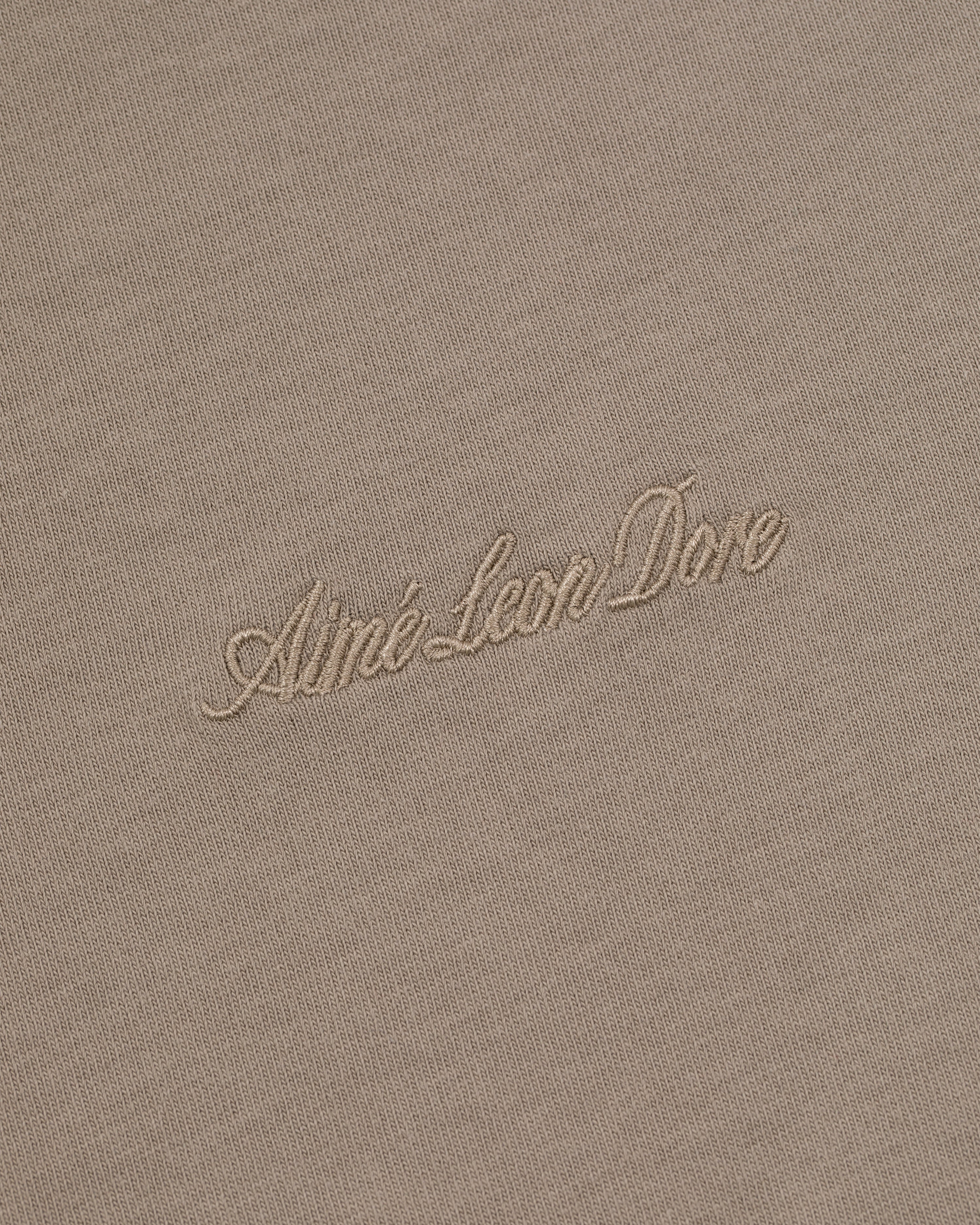 Beige Embroidered Logo Tee with Aimé Leon Dore in light cursive embroidery at the center.