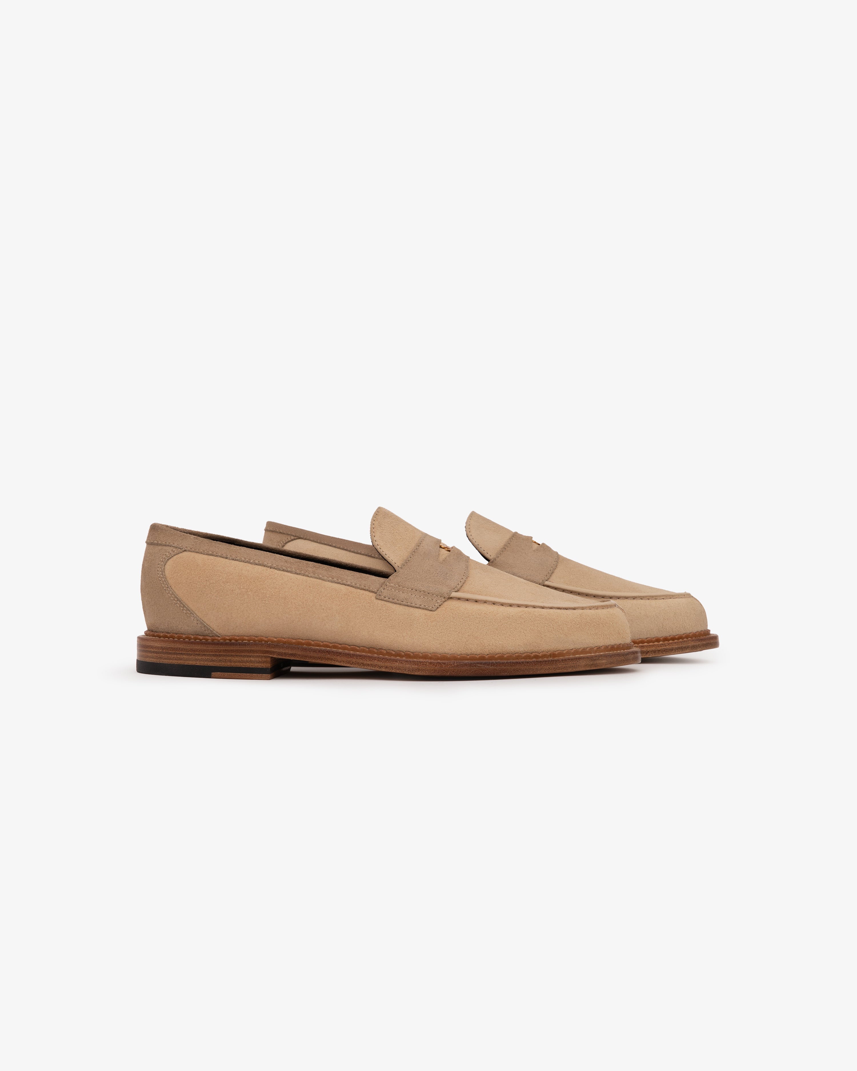 Suede Queens Crest Loafer in beige suede with brown soles and low heels, displayed on a white background.