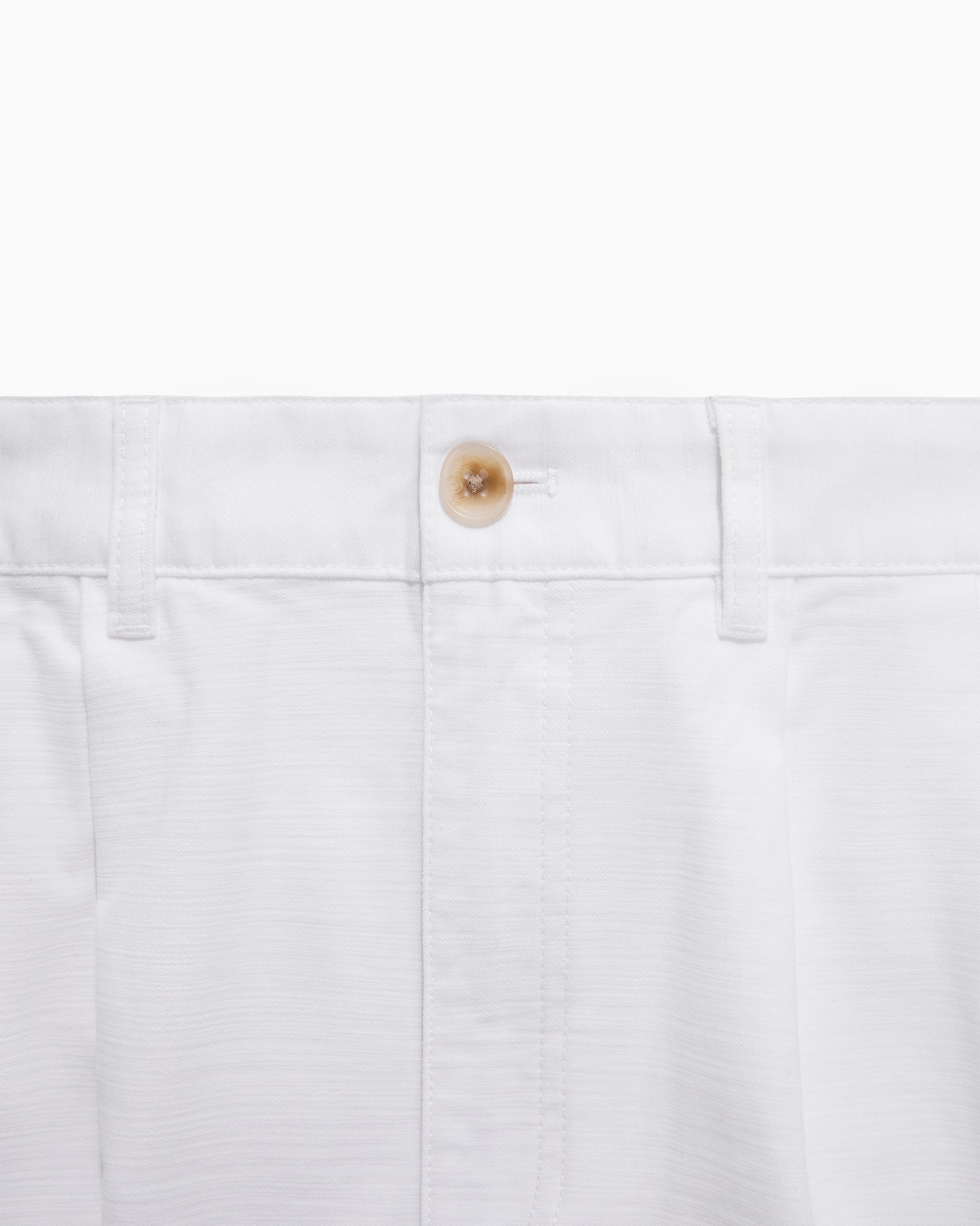 Close-up of Double Pleated Pant’s waistband in white, with a brown button and belt loops.