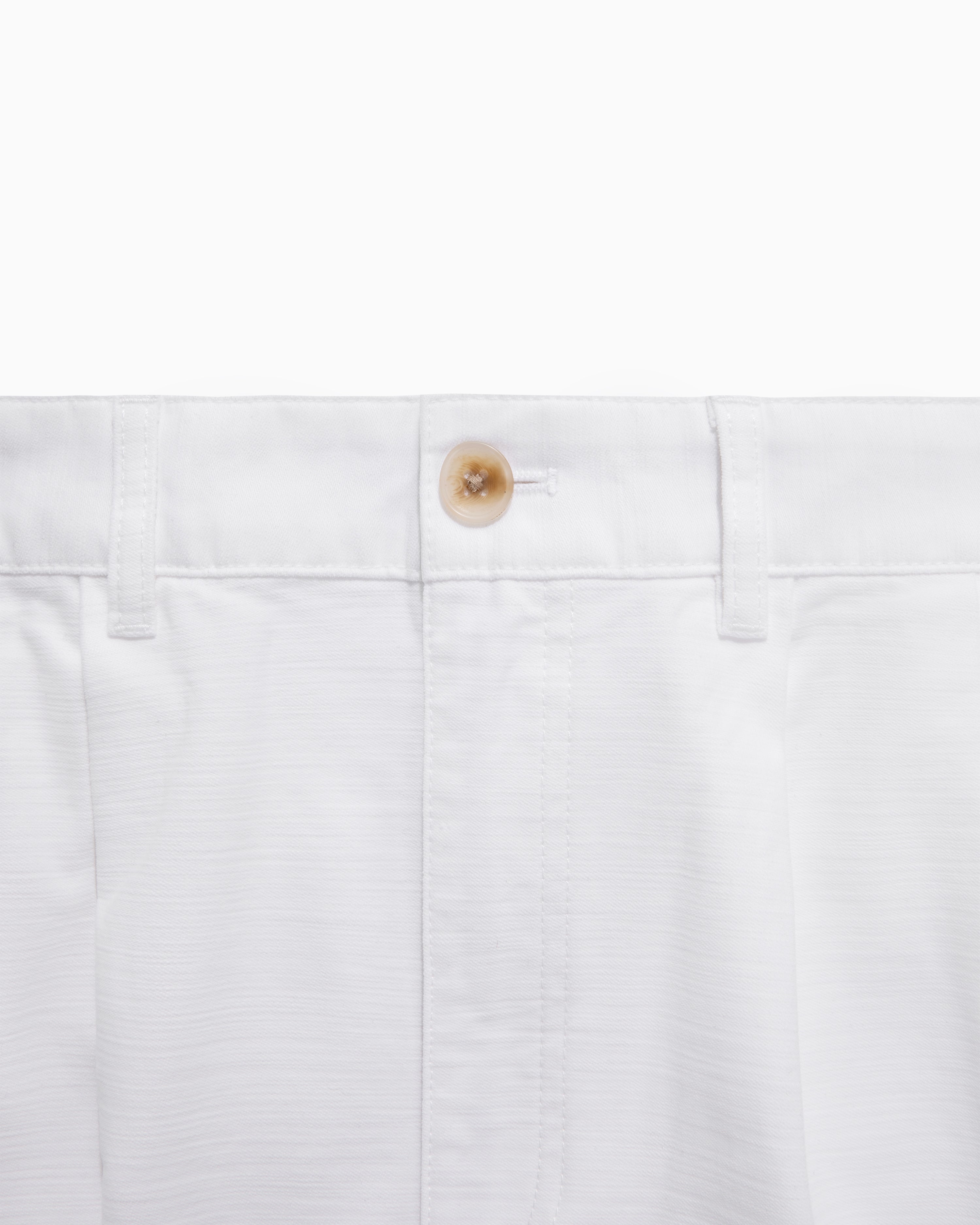 Close-up of Double Pleated Pant’s waistband in white, with a brown button and belt loops.