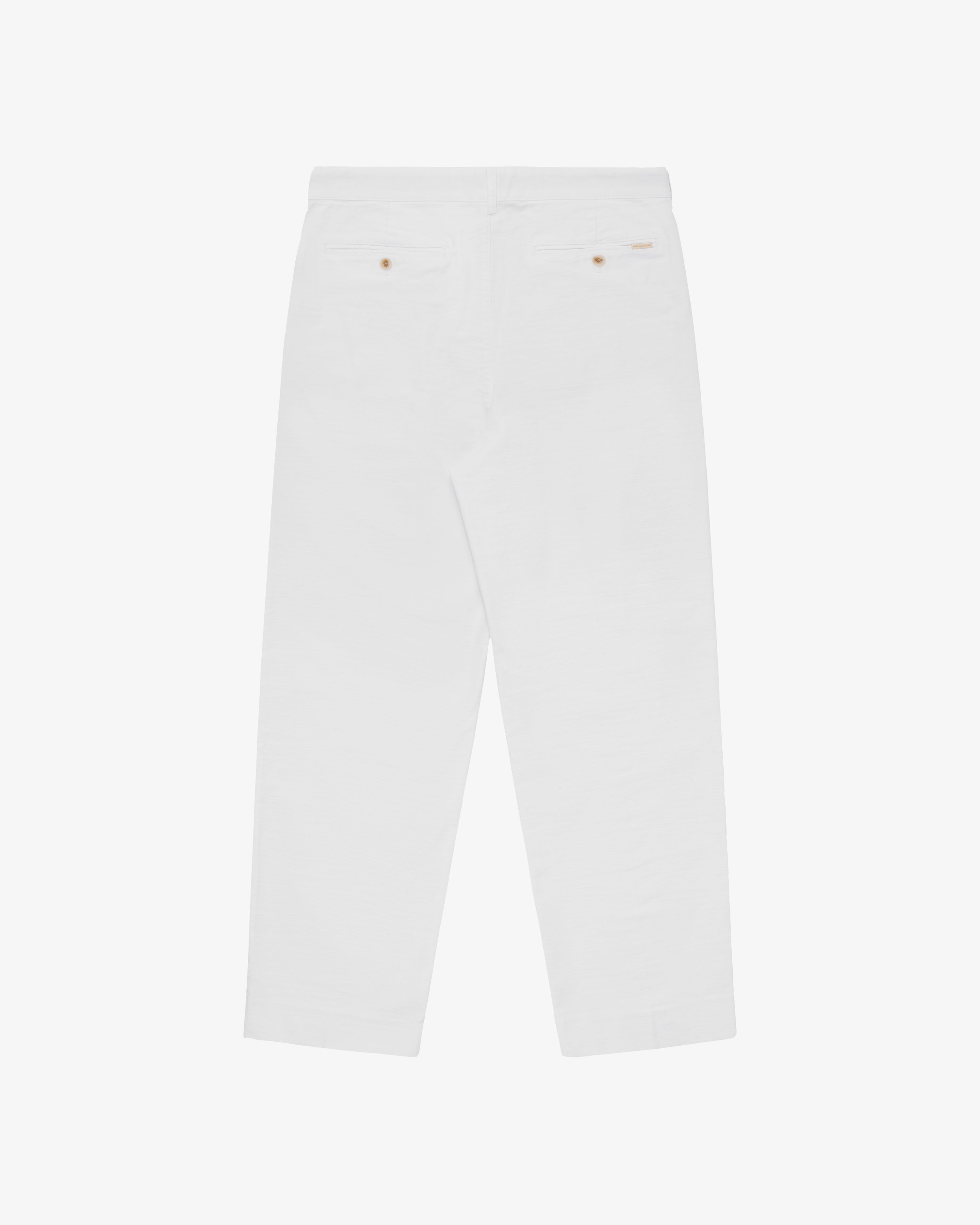 Double Pleated Pant in white, back view with two buttoned welt pockets on a plain background.