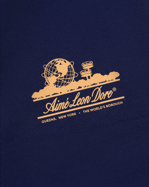 Gold Aimé Leon Dore logo featuring globe and skyline on dark blue Unisphere Sweatpants; reads Queens, New York.