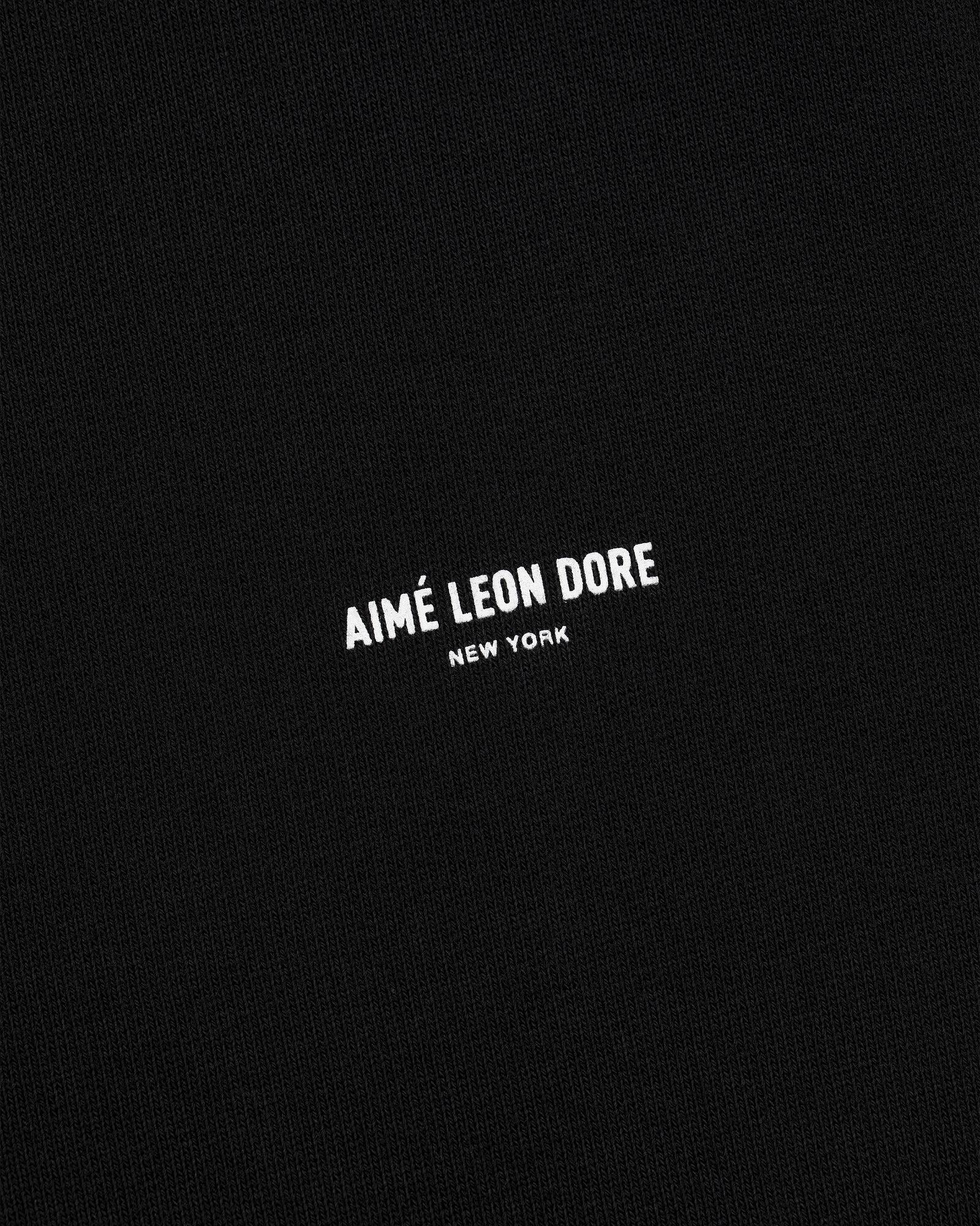 Black fabric sweatpants with small white AIMÉ LEON DORE NEW YORK logo centered on the front.
