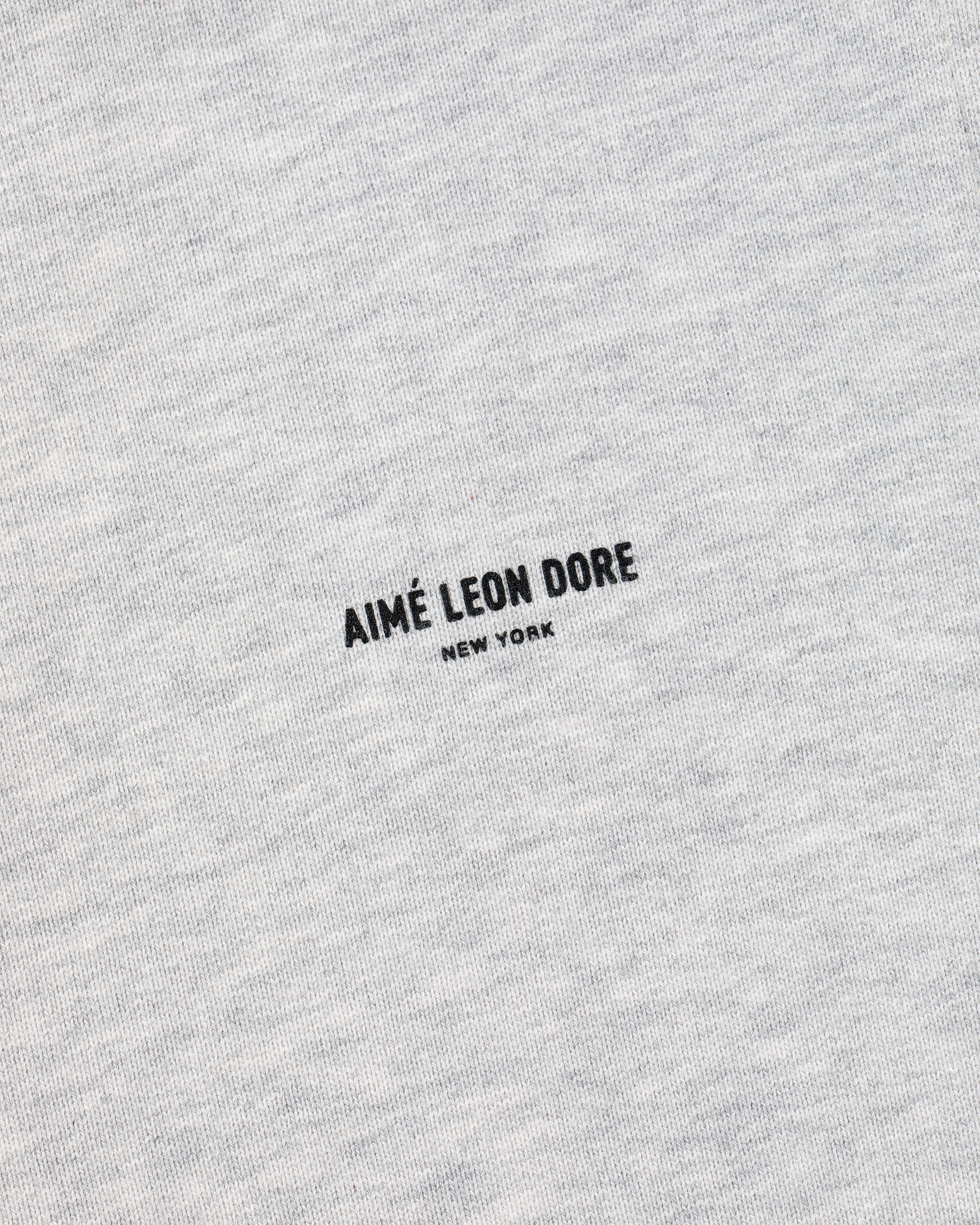 Close-up of heather gray Micro Logo Sweatpants with AIMÉ LEON DORE NEW YORK printed in black at the center.