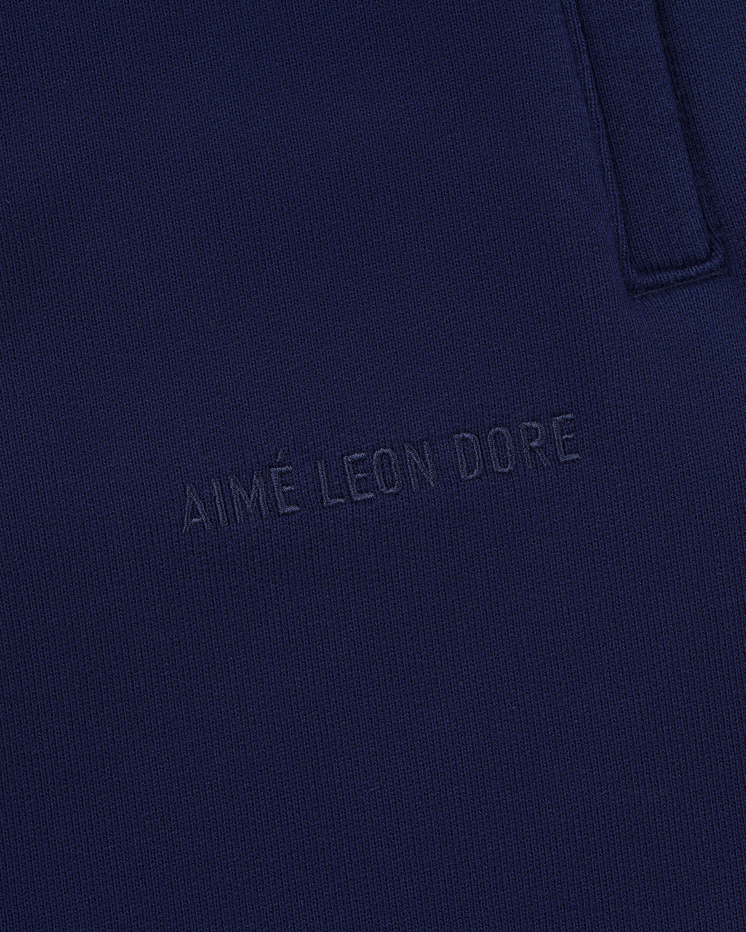 Close-up of Tonal Logo Sweatpants in navy blue with AIMÉ LEON DORE subtly embossed on the fabric.