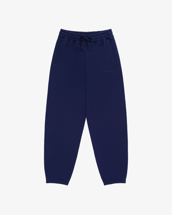 Tonal Logo Sweatpants in navy blue with elastic waistband, drawstring, side pockets, and elastic cuffs on white background.