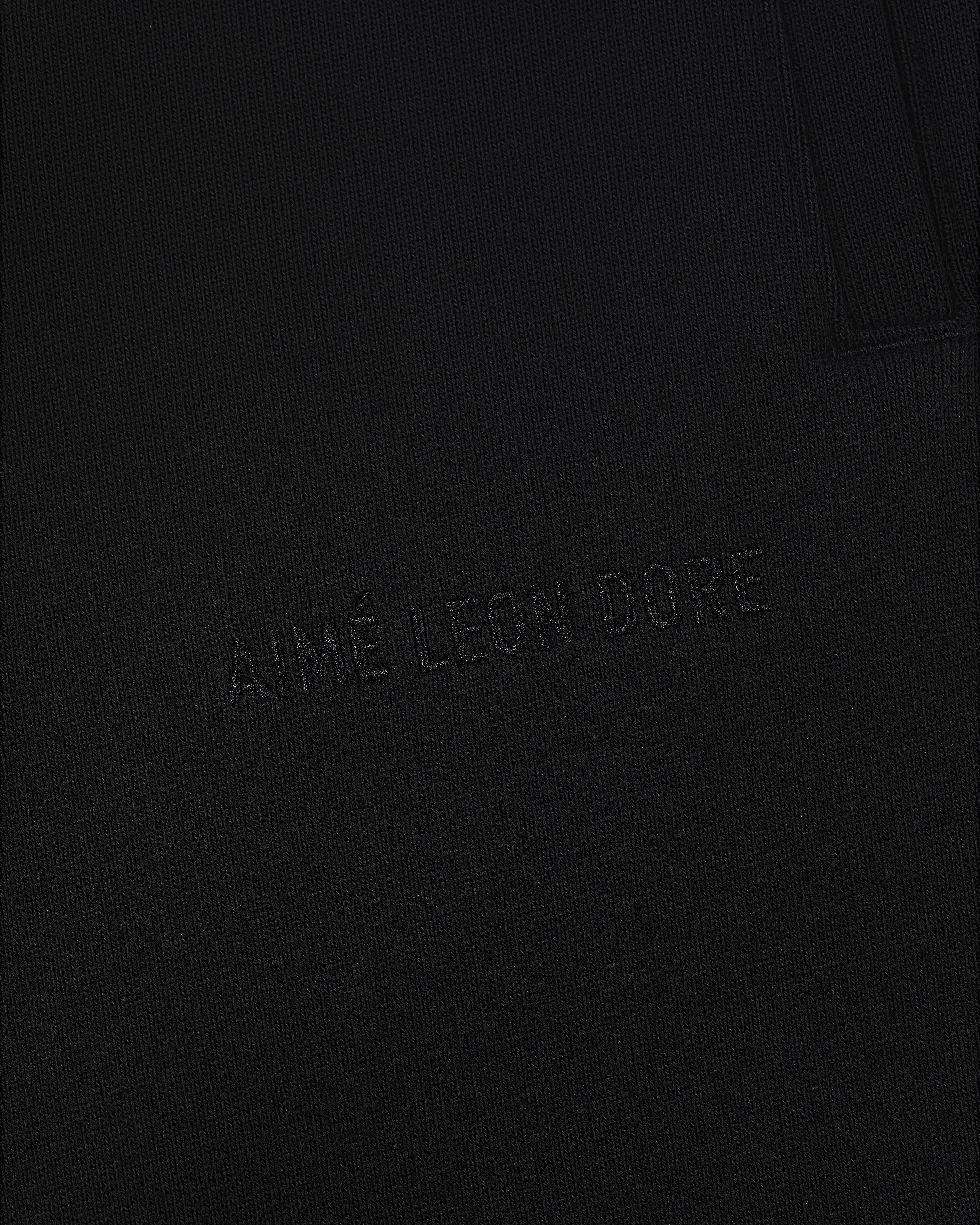 Close-up of Tonal Logo Sweatpants with AIMÉ LEON DORE subtly embroidered on black textured fabric.