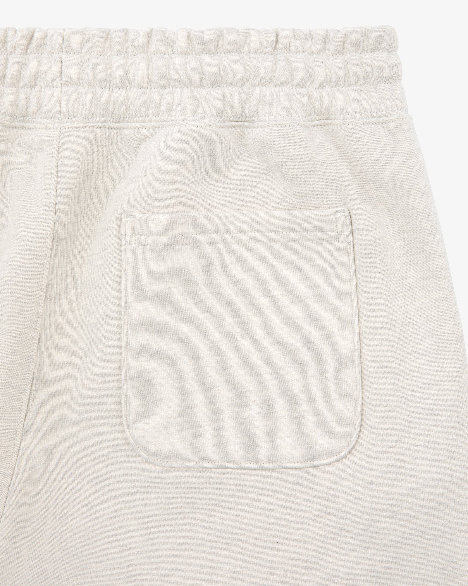 Close-up of the back pocket and elastic waistband on Tonal Logo Sweatpants in light beige.