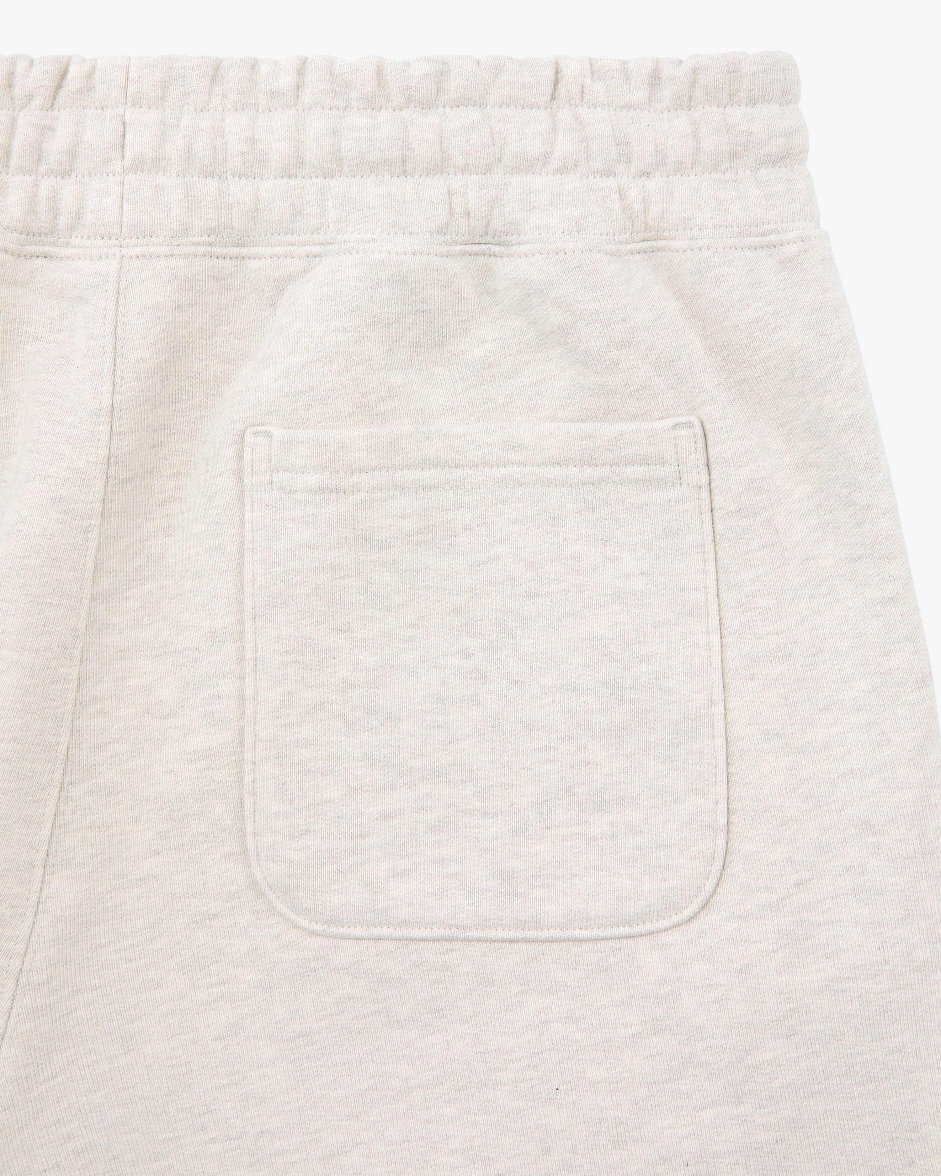 Close-up of the back pocket and elastic waistband on Tonal Logo Sweatpants in light beige.
