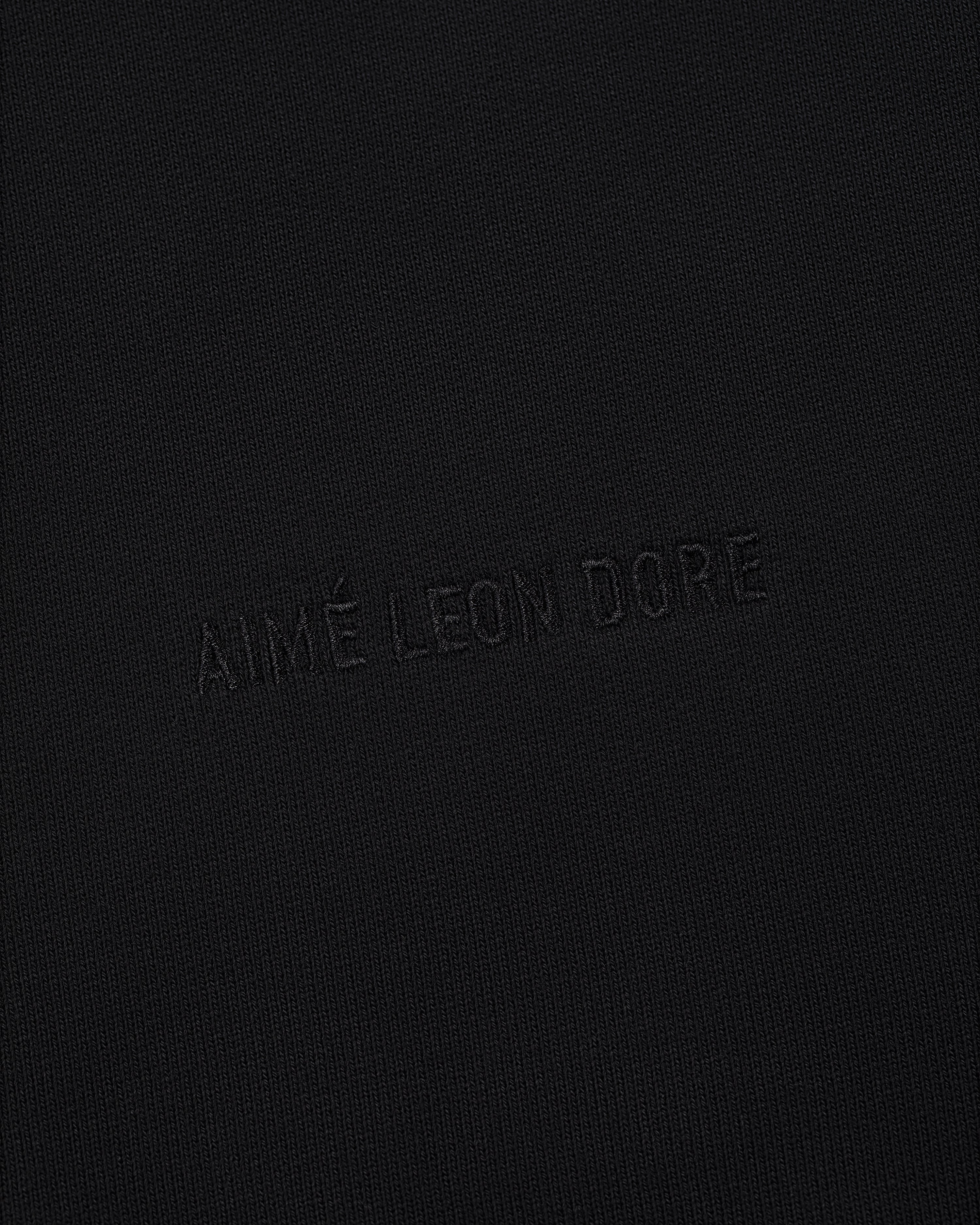 The Tonal Logo Hoodie features black fabric with a subtle, matching black AIMÉ LEON DORE embossed logo for a minimal look.