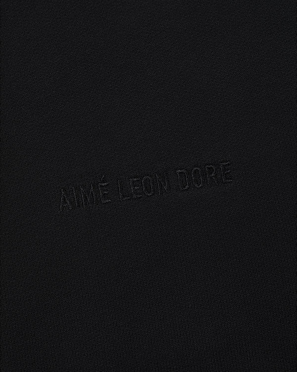 The Tonal Logo Hoodie features black fabric with a subtle, matching black AIMÉ LEON DORE embossed logo for a minimal look.