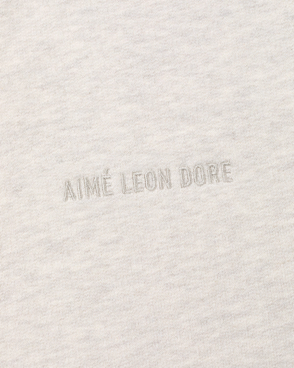 Close-up of the Tonal Logo Hoodie’s light gray fabric with matching AIMÉ LEON DORE embroidery at the center.