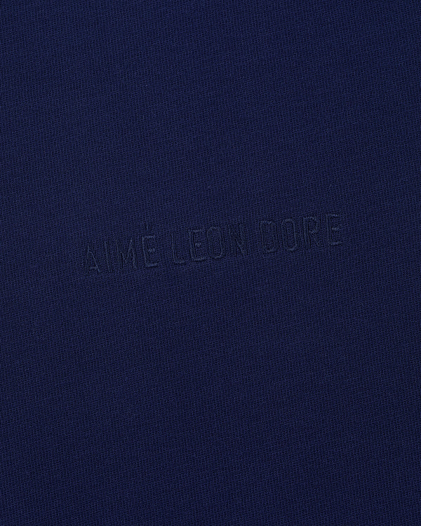 Close-up of the Tonal Logo Tee featuring AIMÉ LEON DORE subtly embroidered in matching dark blue thread.