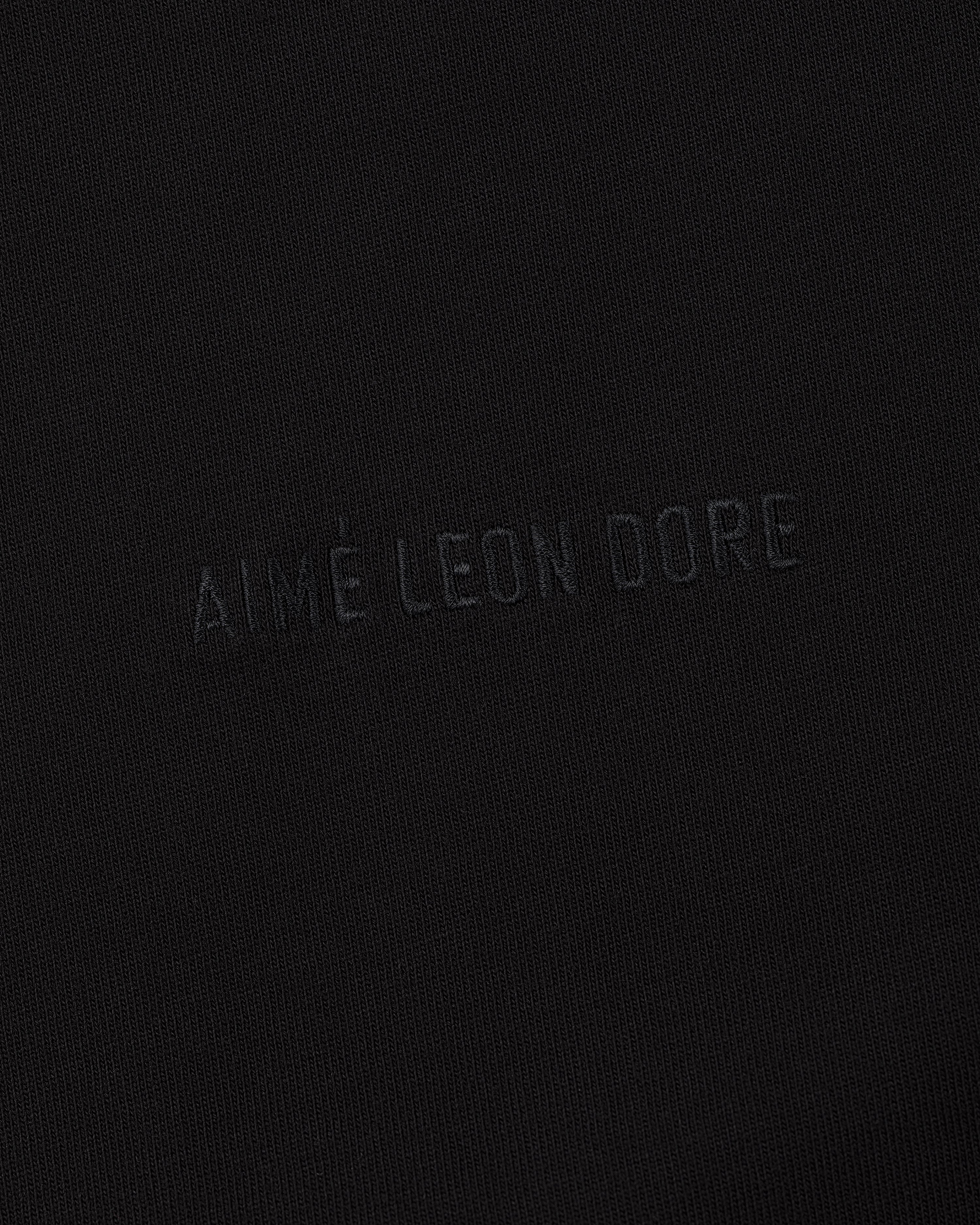 Close-up of black fabric on the Long-Sleeve Tonal Logo Tee with AIMÉ LEON DORE subtly embossed at the center.