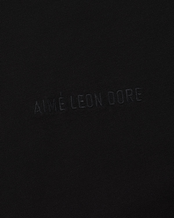 Close-up of black fabric on the Long-Sleeve Tonal Logo Tee with AIMÉ LEON DORE subtly embossed at the center.